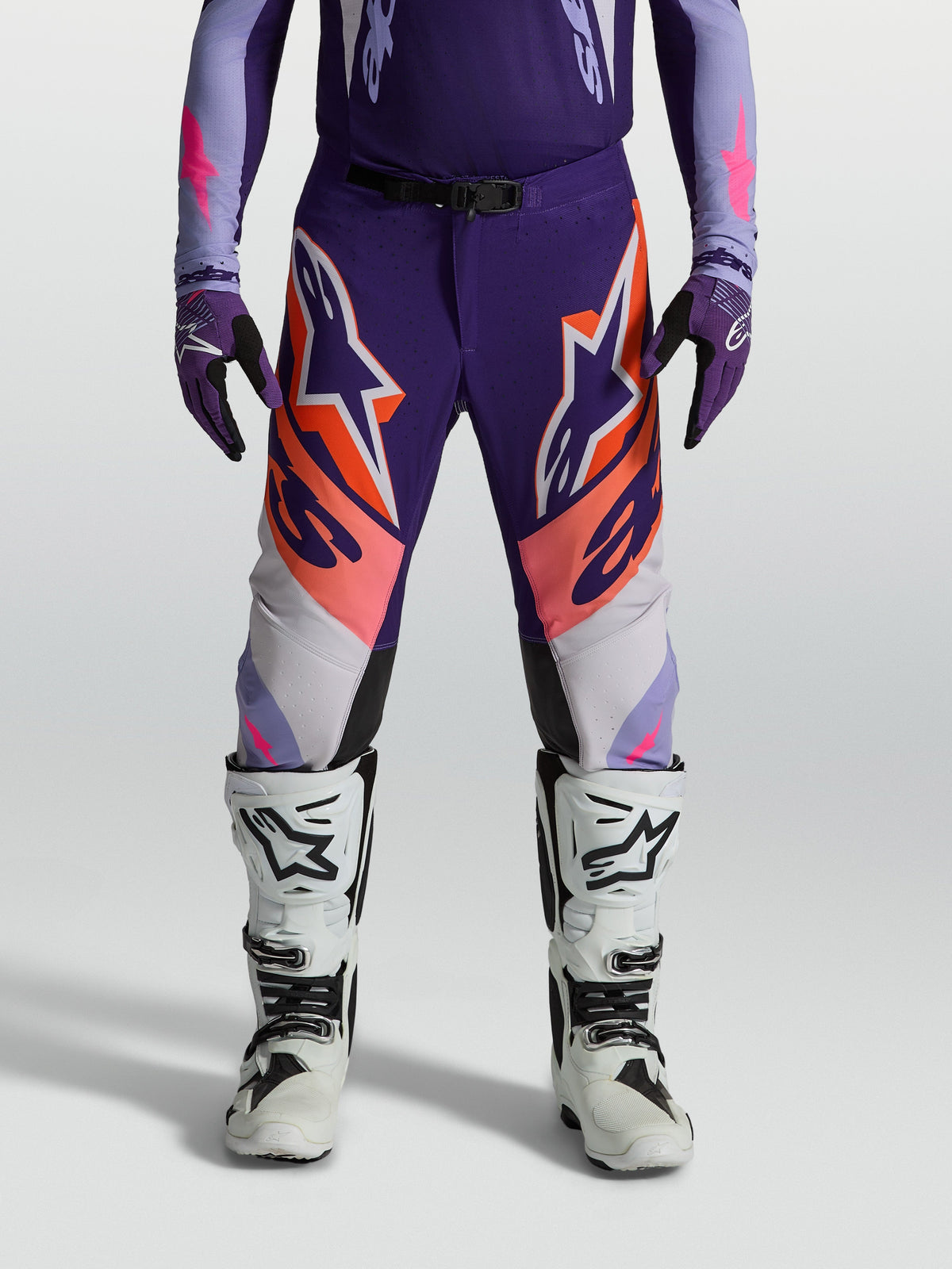 Spodnie Supertech Dyna, męskie spodnie motocrossowe Alpinestars, fioletowe i różowe fluo, sportowy krój z elastycznego materiału ripstop, grafiki z logo Astars, profesjonalna odzież off-road.