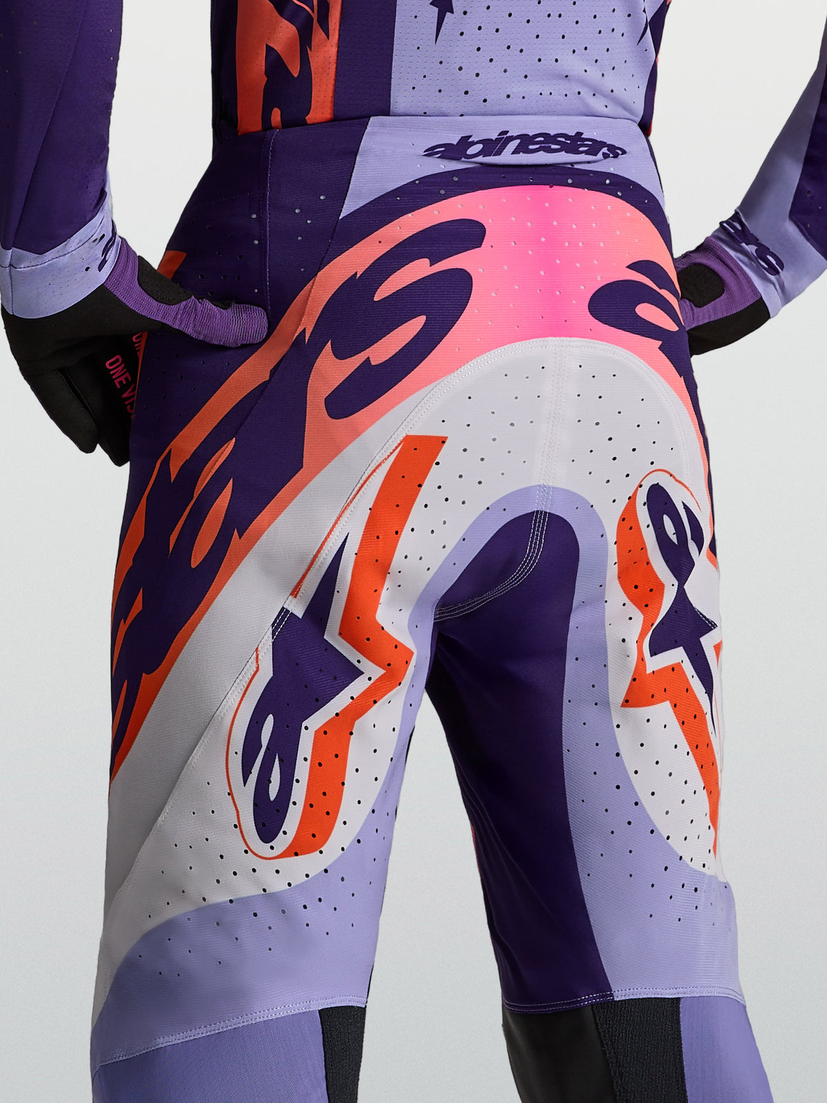 Spodnie Alpinestars Supertech Dyna, męskie spodnie motocrossowe, fioletowe i różowe fluo, wentylowana konstrukcja z perforacjami, profesjonalny krój wyścigowy.