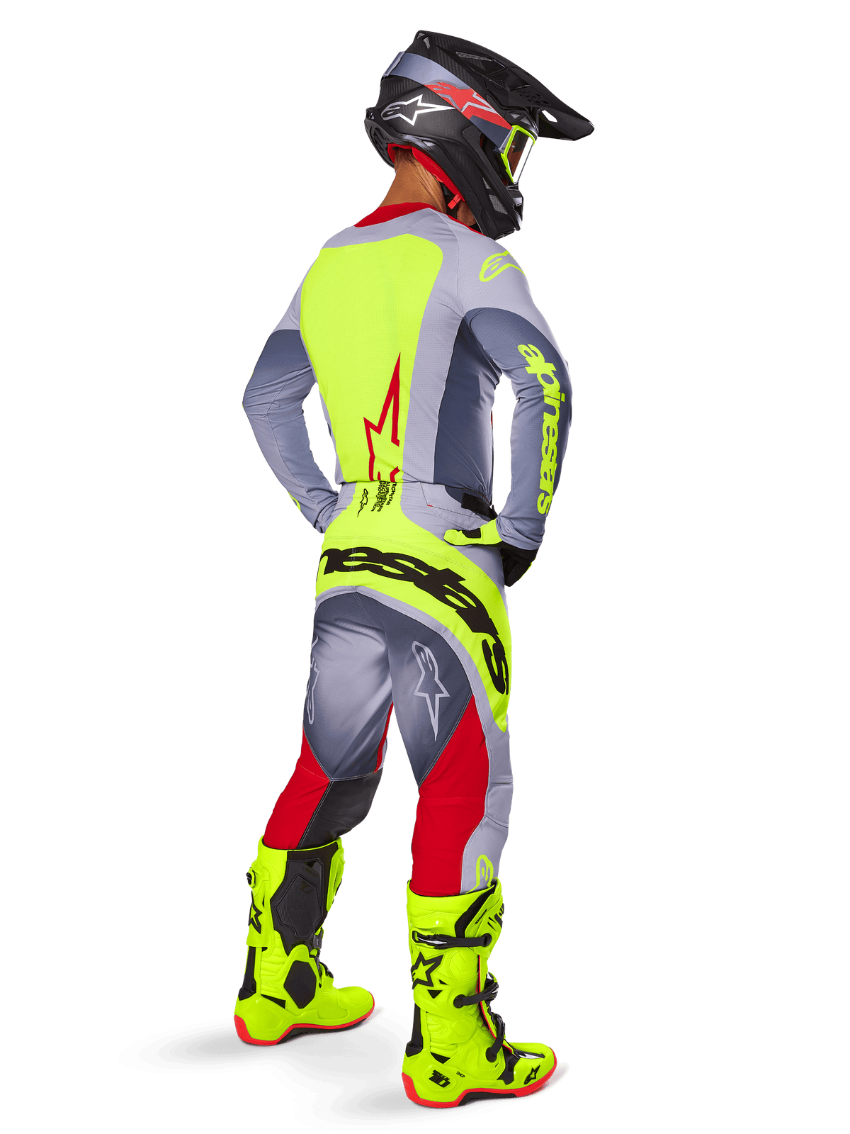 Motocross rider wearing the Alpinestars 2025 Techstar Melt Gear Set, viewed from the back. Gray jersey with a neon yellow back panel and red star logo, gray and red pants with bold neon yellow 'Alpinestars' branding across the seat, bright neon yellow motocross boots, and matching helmet.