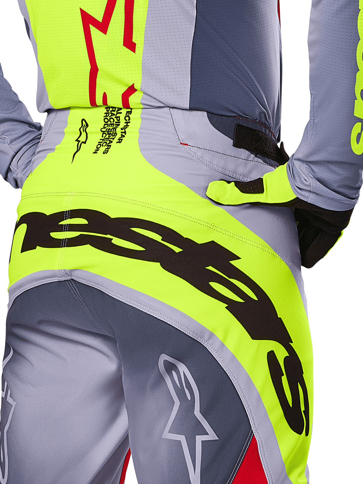Spodnie Alpinestars Techstar Melt 2025, zbliżenie na tył i okolicę pasa, szaro-neonowożółty design z dużym czarnym brandingiem, logotypy gwiazdy i tekst race-spec, wysokiej klasy odzież motocrossowa