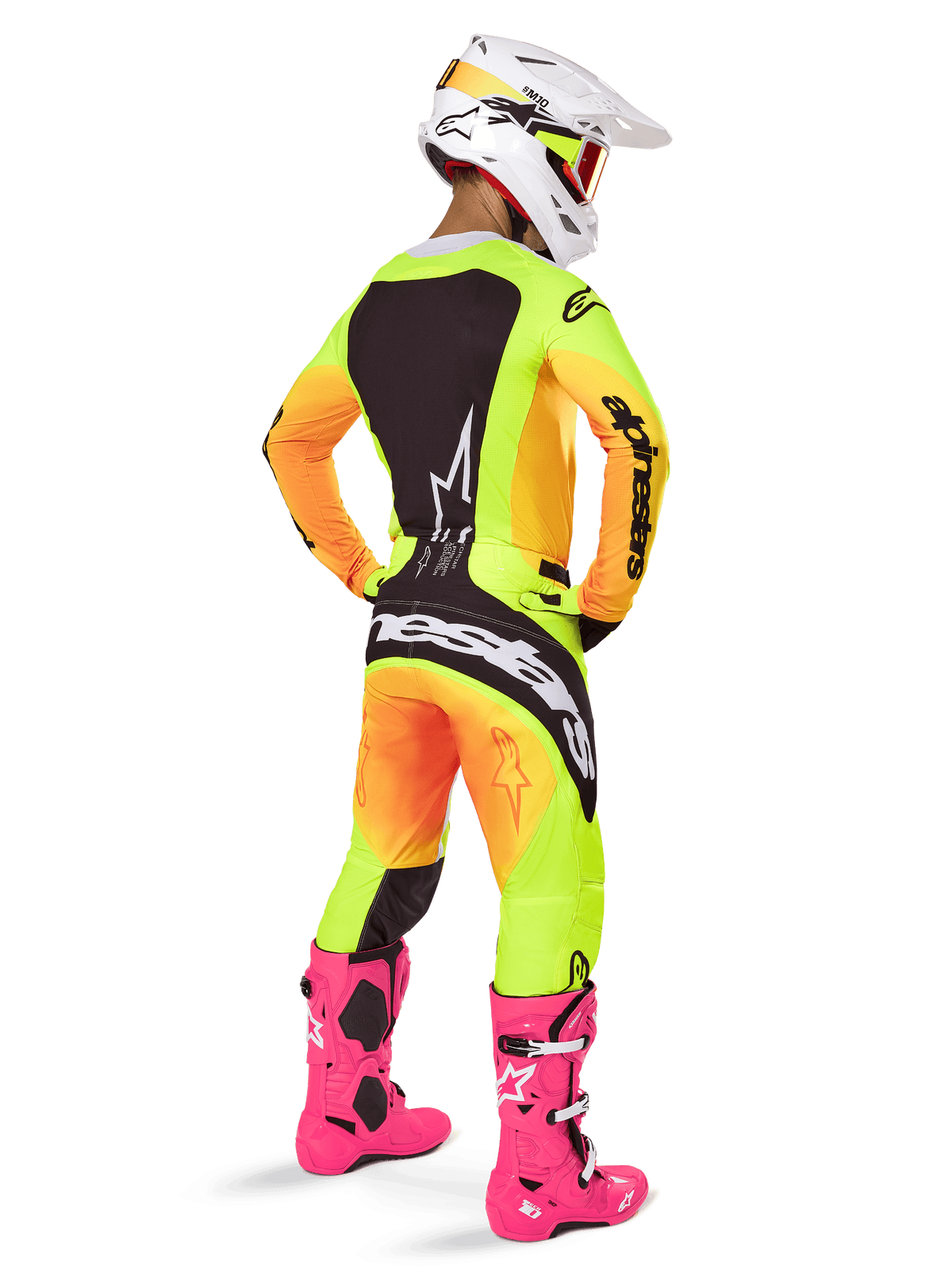 Motocyklista motocrossowy widziany od tyłu w zestawie Alpinestars 2025 Techstar Melt, żółto-pomarańczowa koszulka i spodnie z gradientem i czarnymi panelami, biały kask z czerwonymi goglami, jaskraworóżowe buty, profesjonalny strój wyścigowy do jazdy terenowej