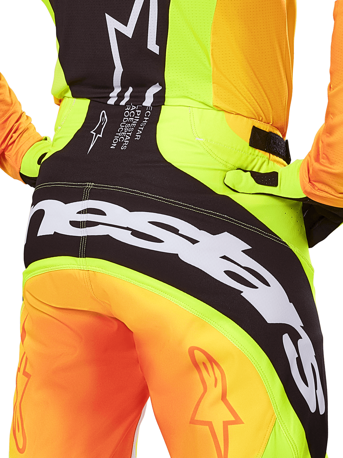 Spodnie Alpinestars Techstar Melt 2025, spodnie motocrossowe, zbliżenie na tył, neonowy żółty i pomarańczowy z czarnymi panelami, duże białe logo Alpinestars na siedzeniu, profesjonalna odzież do jazdy terenowej