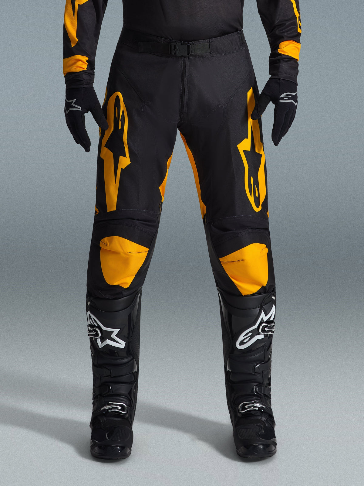 Alpinestars 2026 Racer Riway Pants, Motocross Pants, Yellow and Black, worn with black motocross gloves and black boots with white logos, featuring large yellow Alpinestars logos on the thighs and yellow knee panels, durable design for off-road racing performance