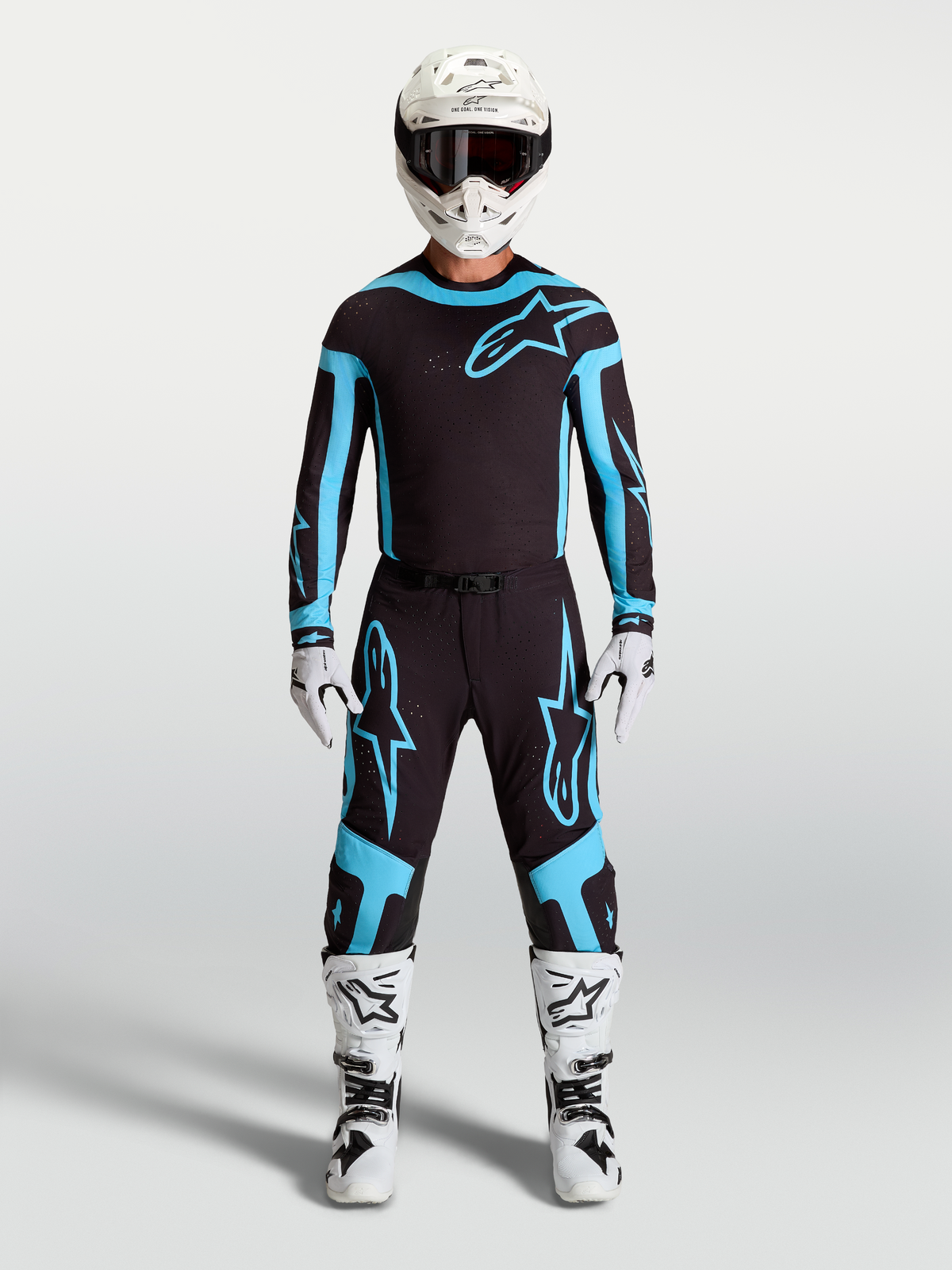 Spodnie Alpinestars Supertech Vesta, męskie spodnie motocrossowe, czarne i turkusowe, prezentowane na modelu w pełnym stroju wyścigowym, lekka elastyczna konstrukcja rip-stop.