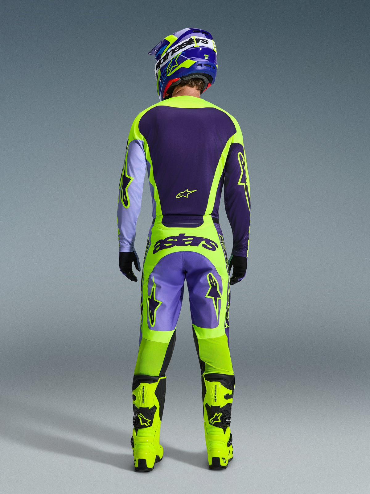 Alpinestars 2026 Racer Portl Pants, Motocross Pants, Purple Yellow Fluo, full rear view of a rider wearing the complete gear set including matching jersey, helmet, and bright yellow boots, featuring bold 'astars' branding and star logos.