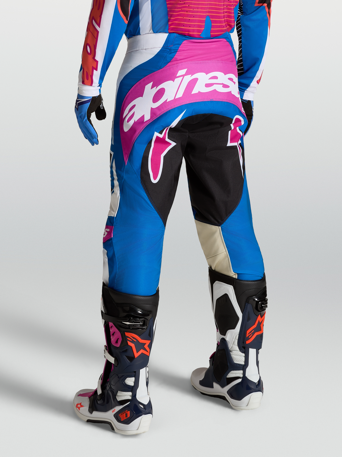 Alpinestars Spodnie Techstar Maven, męskie spodnie motocrossowe, niebieskie i różowe, z dużym logo Alpinestars na siedzeniu i konstrukcją kolan 3D Babel, widok od tyłu.