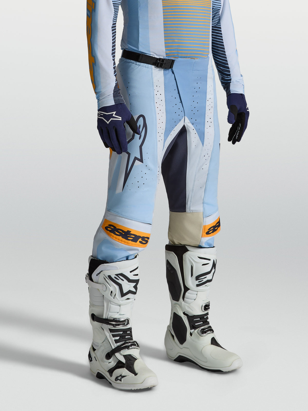 Spodnie Alpinestars Techstar Maven, męskie spodnie motocrossowe, jasnoniebieskie i pomarańczowe, ergonomiczny krój wyścigowy, laserowe perforacje dla lepszej wentylacji, klamra magnetyczna SX2 i skórzane panele na kolanach.