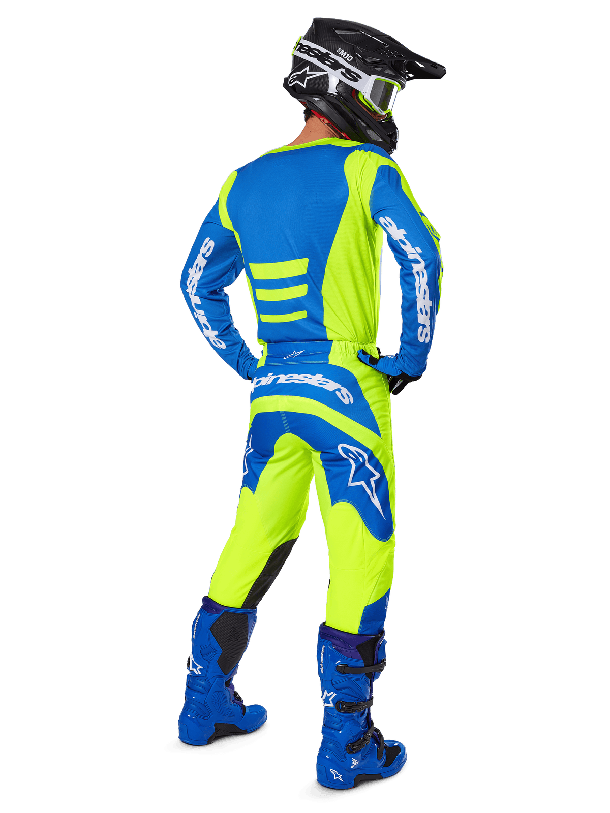 Zawodnik motocrossowy widziany od tyłu w spodniach Alpinestars 2025 Fluid Haul i dopasowanej koszulce w kolorach żółtym fluo i niebieskim, w połączeniu z niebieskimi butami i czarnym kaskiem Alpinestars, profesjonalny strój do wyścigów terenowych