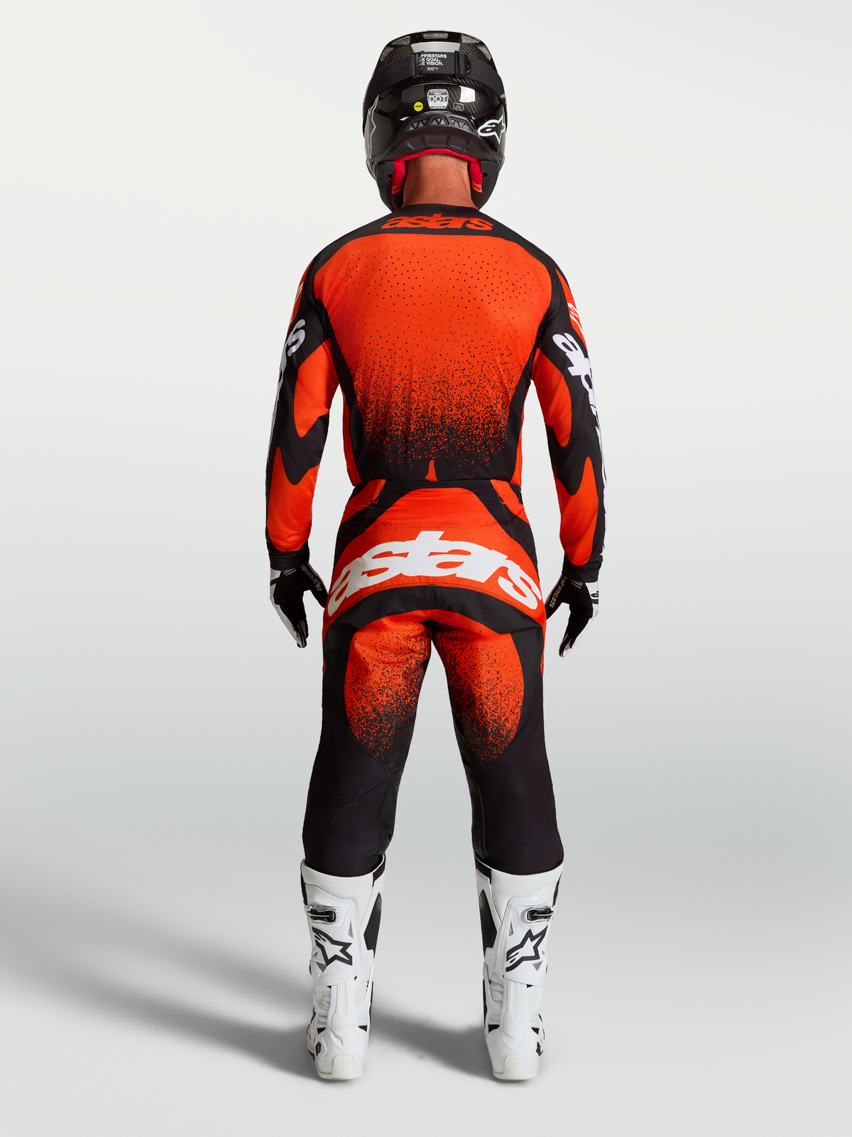 Spodnie Alpinestars Techstar Swan, męskie spodnie motocrossowe, czerwone i czarne, widok z tyłu na modelu w białych butach wyścigowych, odzież MX