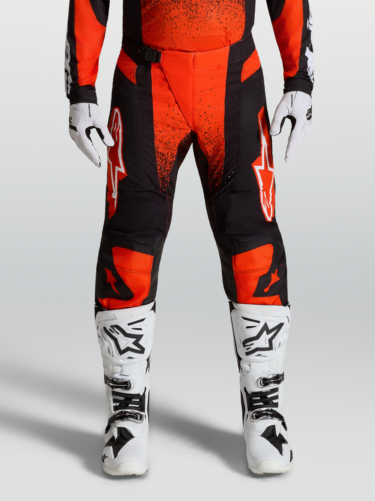 Spodnie Alpinestars Techstar Swan 2027, czerwono-czarne spodnie motocrossowe MX, z białymi butami i rękawicami.