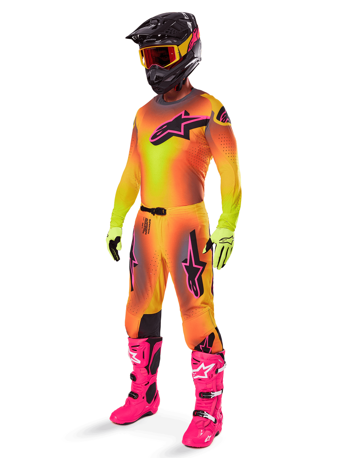Alpinestars Supertech Lipan Pants 2025, spodnie motocrossowe, żółto-różowe, noszone jako część pełnego zestawu z dopasowaną koszulką z gradientem, jaskraworóżowymi butami, żółtymi rękawicami i czarnym kaskiem, z wyraźnymi czarnymi logotypami i sportowym krojem do wyścigów off-road