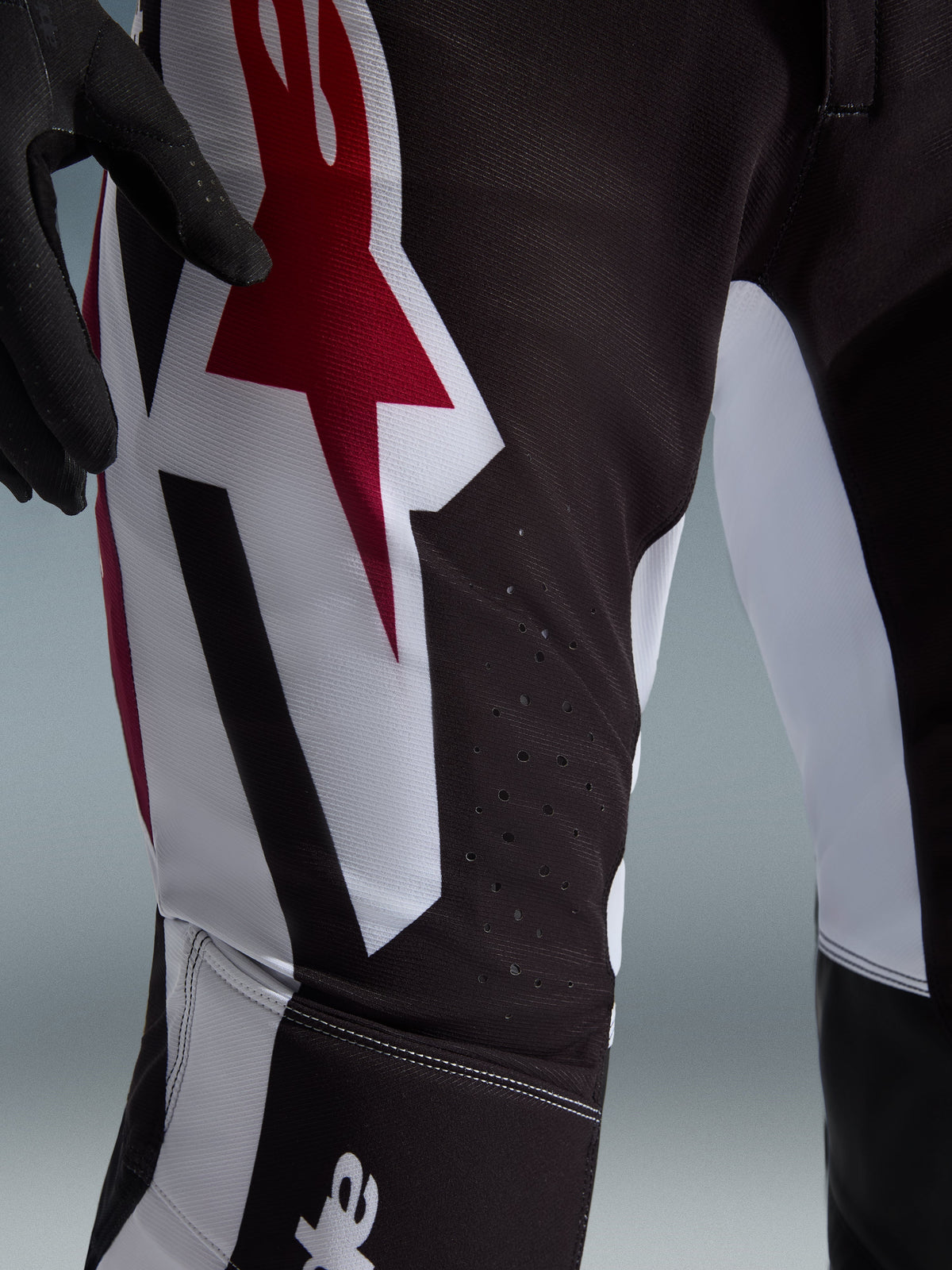 Alpinestars 2026 Supertech AFD Vista Pants, Motocross Pants, Black Red and White, close-up of the thigh area featuring a large red and white star logo, laser-cut perforations for airflow, and durable stretch ripstop fabric.