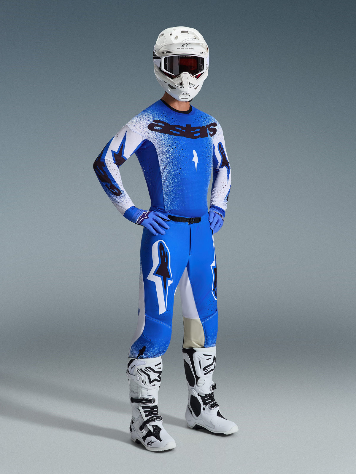 Zawodnik motocrossowy w pełnym stroju wyścigowym, spodnie 2026 Supertech Scenz w kolorze Ucla Blue i białym, dopasowana niebiesko-biała koszulka z logo Astars, biały kask z czerwonymi goglami, biało-czarne buty, profesjonalny zestaw do wyścigów off-road