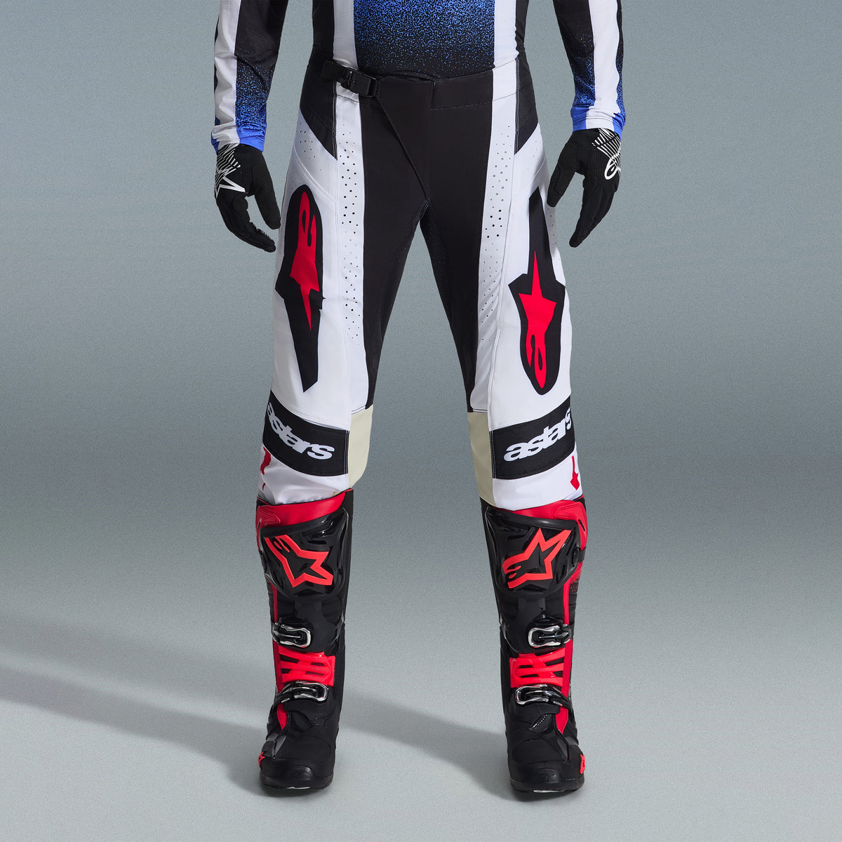 Alpinestars 2026 Techstar Knif Gear Set, odzież motocrossowa, czarno-białe spodnie z dużymi czerwonymi logotypami gwiazdy, noszone z czarno-czerwonymi butami wyścigowymi i czarnymi rękawicami, profesjonalny sportowy krój zapewniający wydajność w terenie