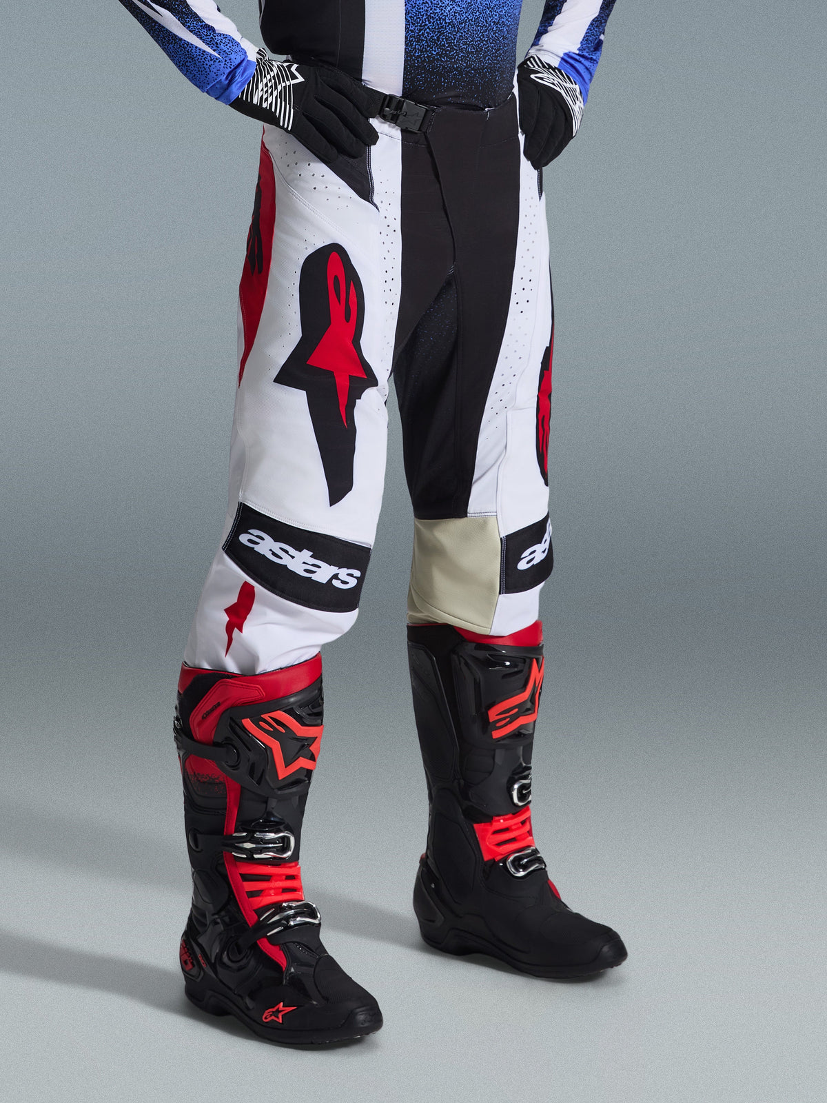 Zestaw Alpinestars 2026 Techstar Knif, spodnie i buty motocrossowe, biało-czarno-czerwone, z wyraźnym brandingiem i konstrukcją z wielu materiałów, noszone z czarnymi rękawicami, profesjonalny zestaw wyścigowy do jazdy off-road.