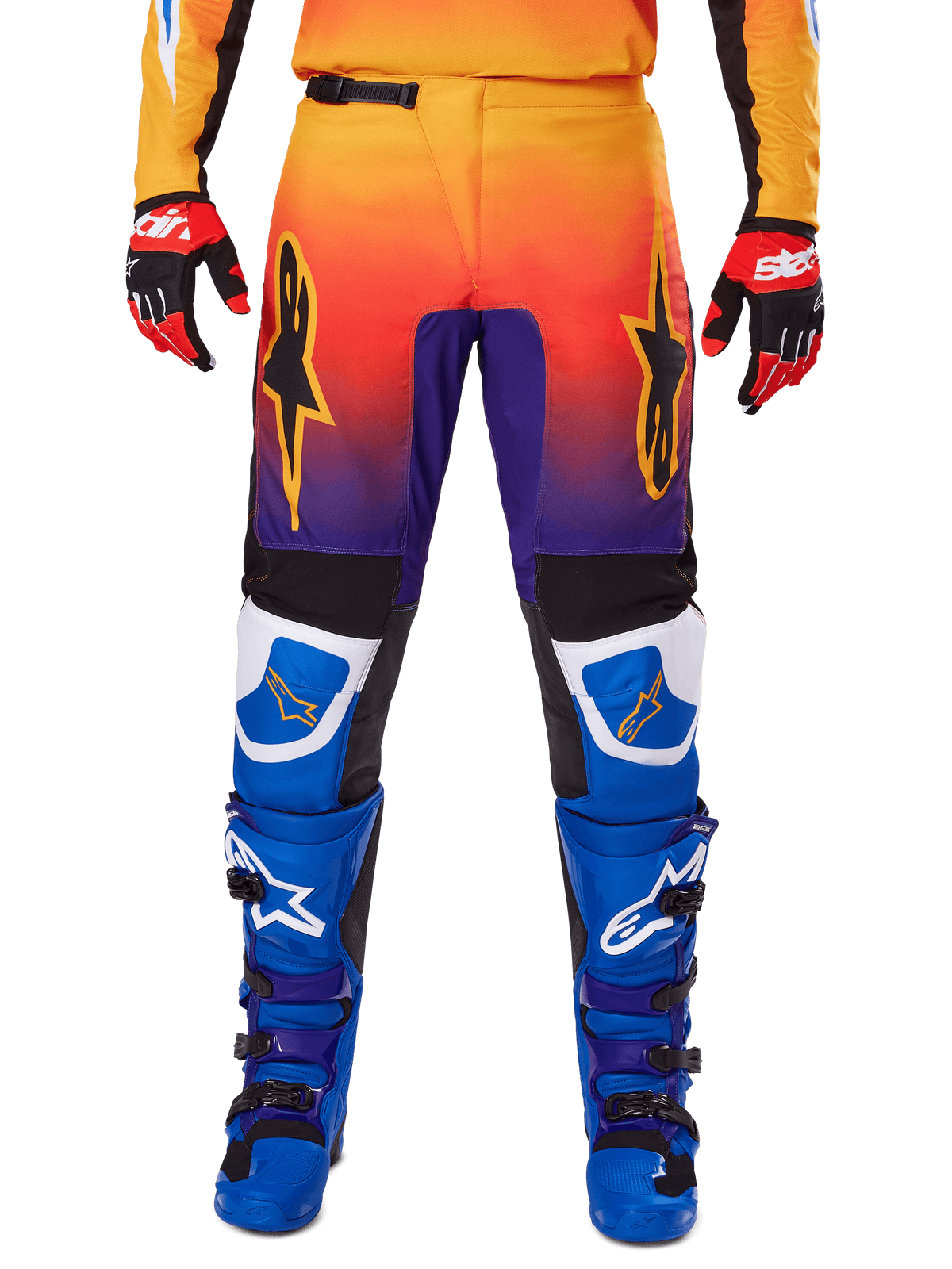 Alpinestars 2025 Fluid Wurx Pants, spodnie motocrossowe, wielokolorowe z gradientem od pomarańczowego do fioletowego i niebieskimi panelami, zestawione z pasującymi niebiesko-fioletowymi butami i czerwono-czarnymi rękawicami, widok z przodu z logo gwiazdy