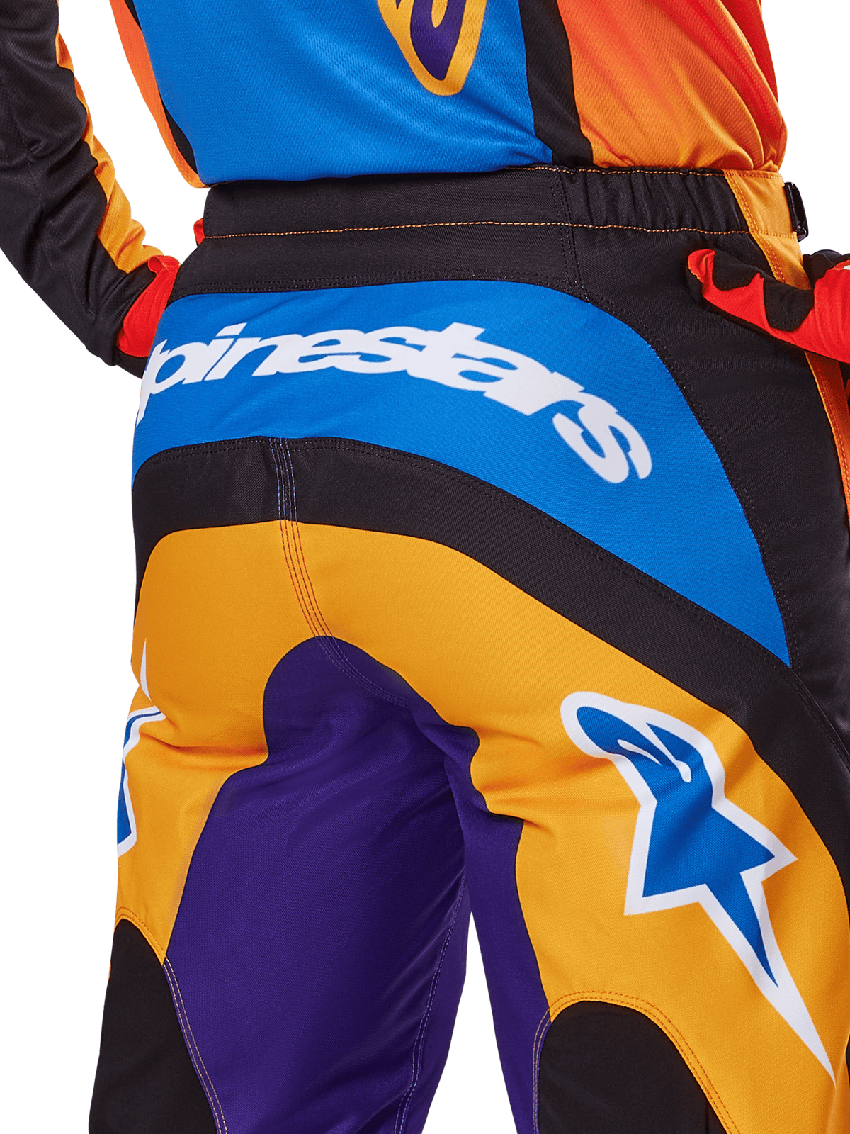 Alpinestars 2025 Fluid Wurx Pants, spodnie motocrossowe, widok z tyłu w kolorach pomarańczowym, niebieskim i fioletowym, z białym logo Alpinestars na siedzeniu i niebieskim logo Astar na nogawce, techniczna konstrukcja do jazdy terenowej