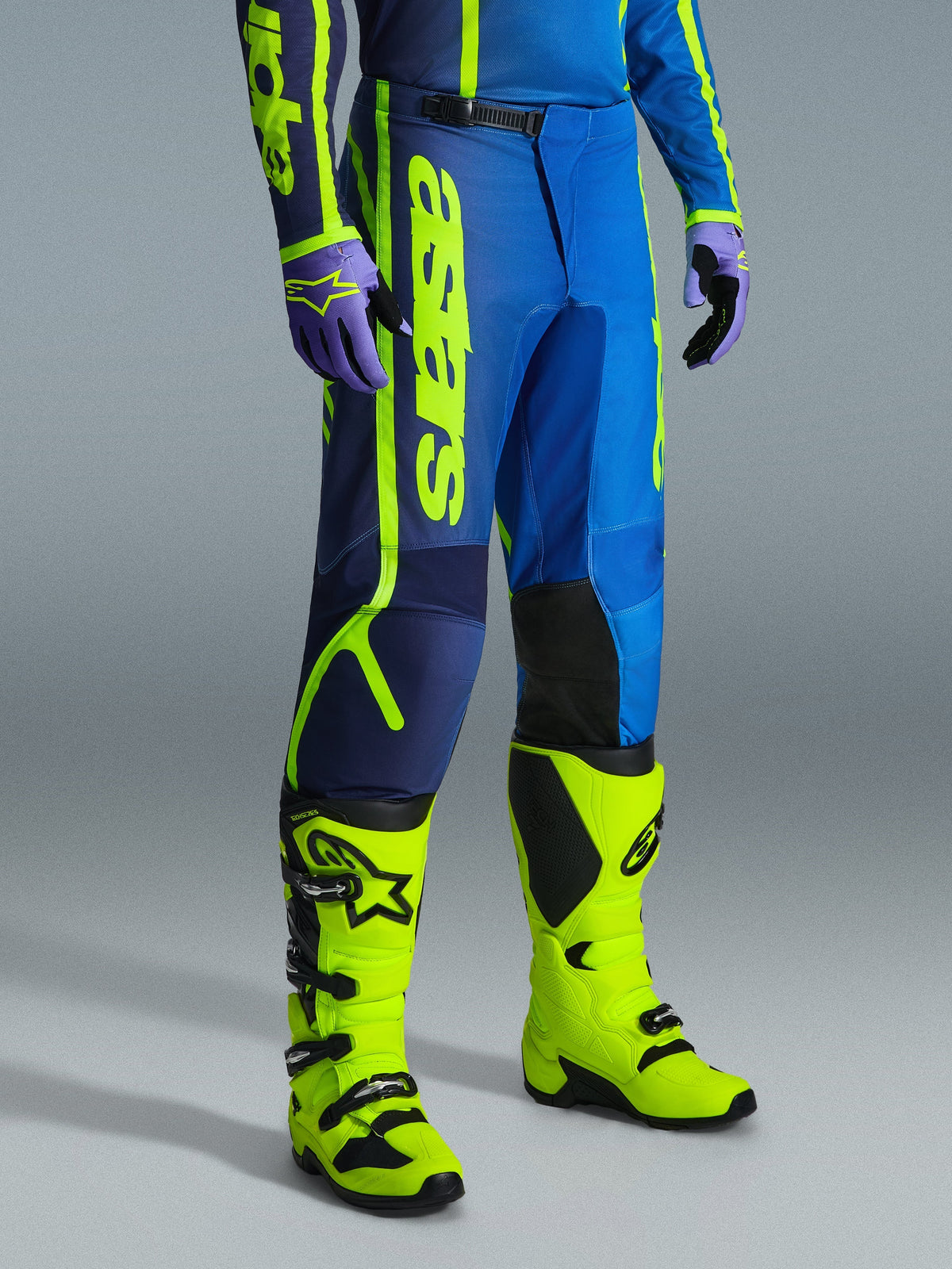 Alpinestars 2026 Fluid Apex Pants, Motocross Pants, Blue and Yellow Fluo, worn with matching gloves and bright yellow fluo boots, featuring bold vertical branding, reinforced knee panels, and a secure ratchet waist closure.