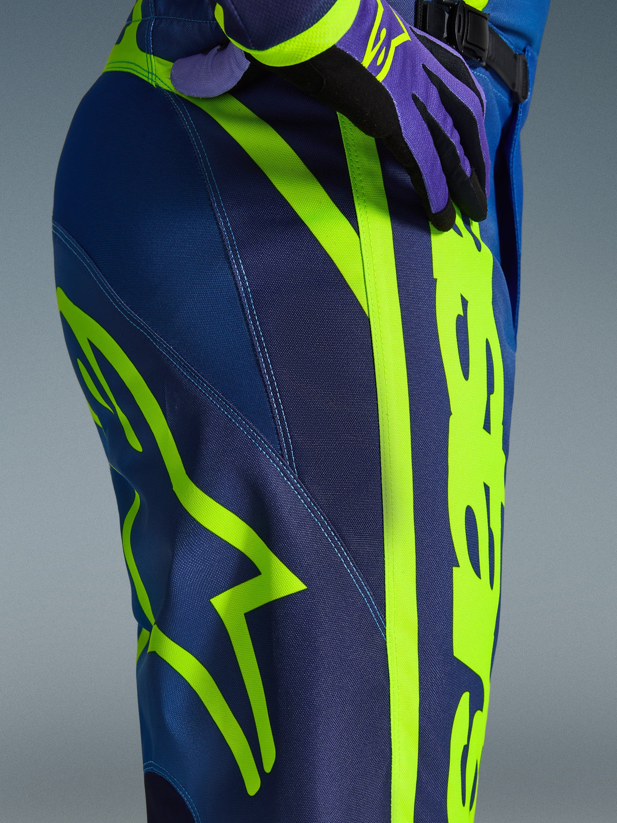 Alpinestars 2026 Fluid Apex Pants, Motocross Pants, Blue and Yellow Fluo, close-up view of the side and hip featuring bold neon yellow Alpinestars branding, durable polyfabric material for off-road riding, part of matching gear set