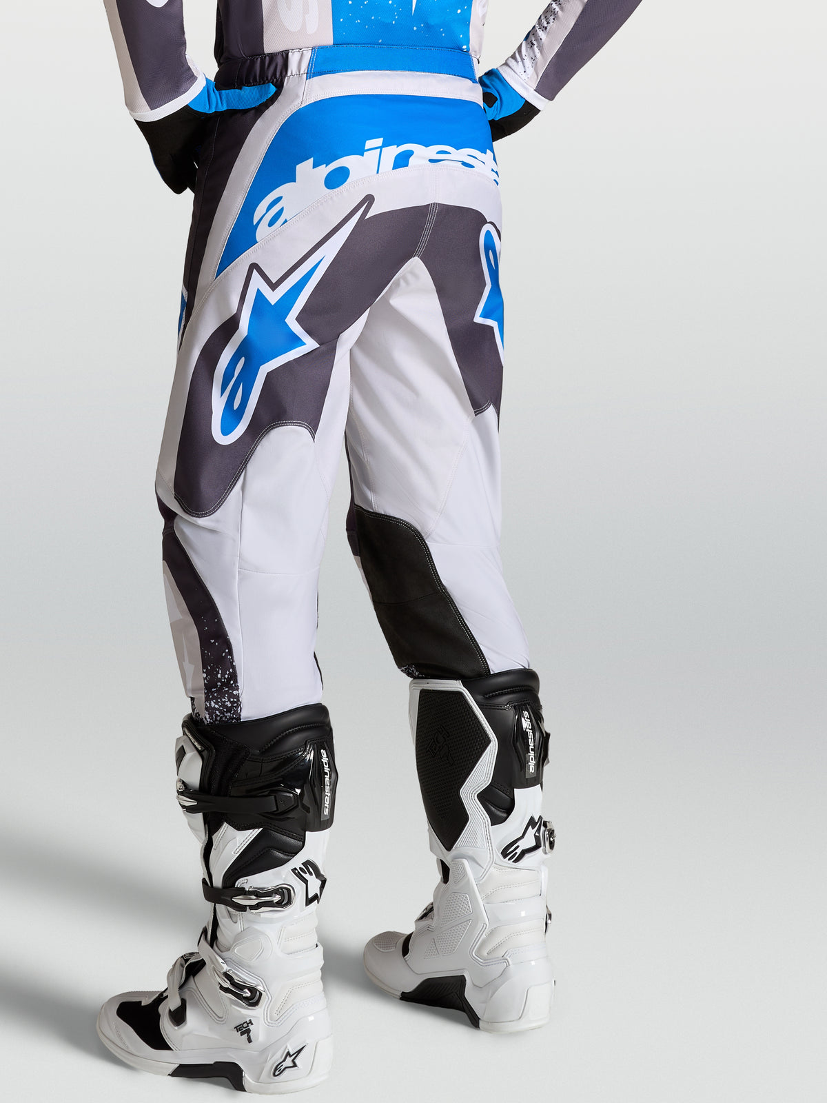 Spodnie Alpinestars Fluid Drag, szare i niebieskie spodnie motocrossowe, widok z tyłu, ergonomiczna konstrukcja wzoru 3D.