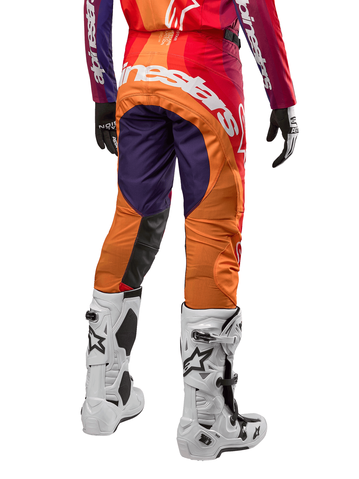 Alpinestars Techstar Pneuma Pants 2024, spodnie motocrossowe, fioletowe, pomarańczowe i granatowe z czerwonymi akcentami, duże białe logo na siedzeniu, widok od tyłu z białymi butami i czarnymi rękawicami, sportowy design