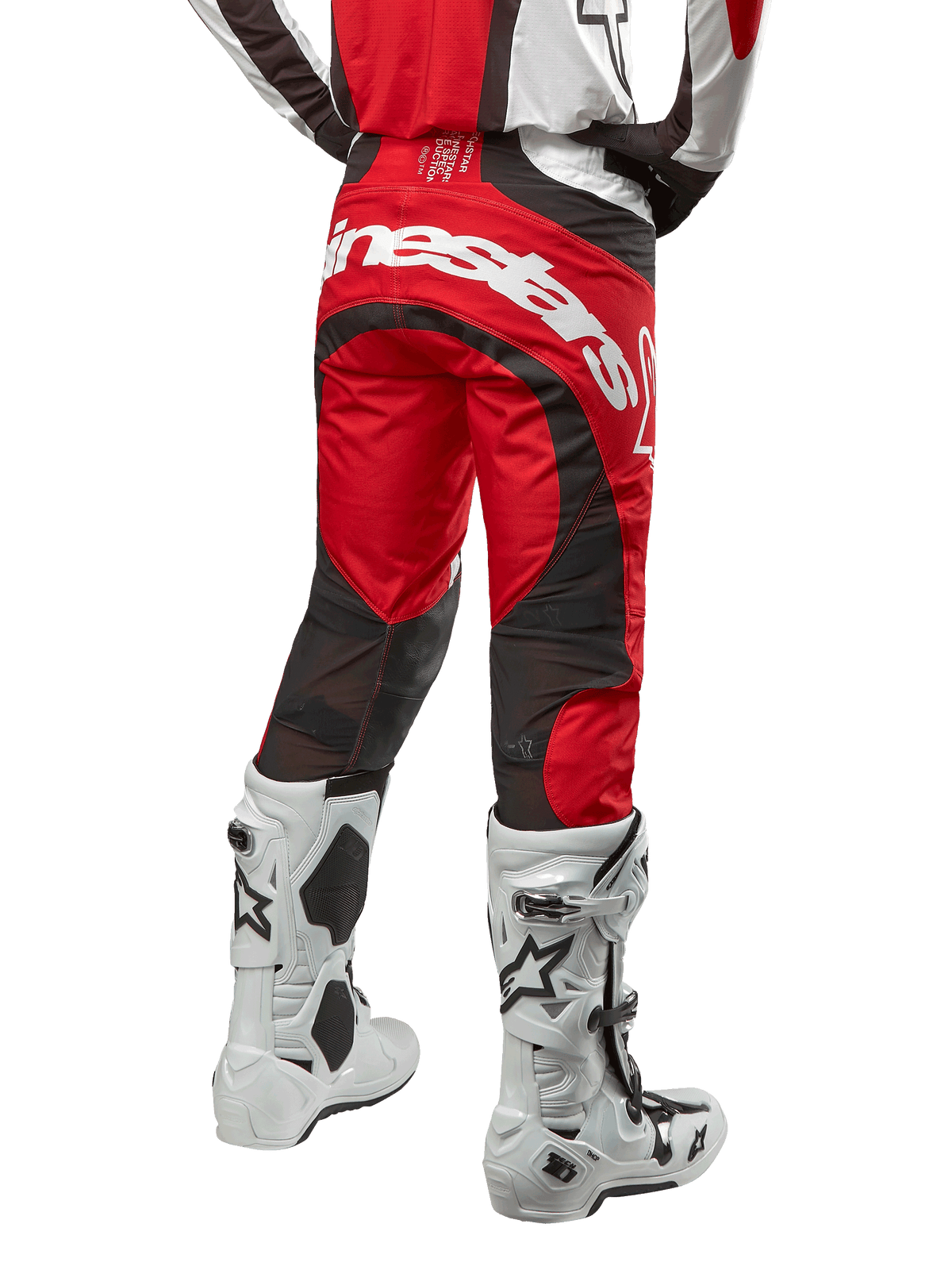 Alpinestars 2024 Techstar Ocuri Pants, spodnie motocrossowe, kolor Mars Red White and Black, widok z tyłu z dużym białym logo Alpinestars na siedzeniu, czarne siatkowe panele wentylacyjne, noszone z biało-czarnymi butami motocrossowymi, sportowy krój race-fit do jazdy terenowej