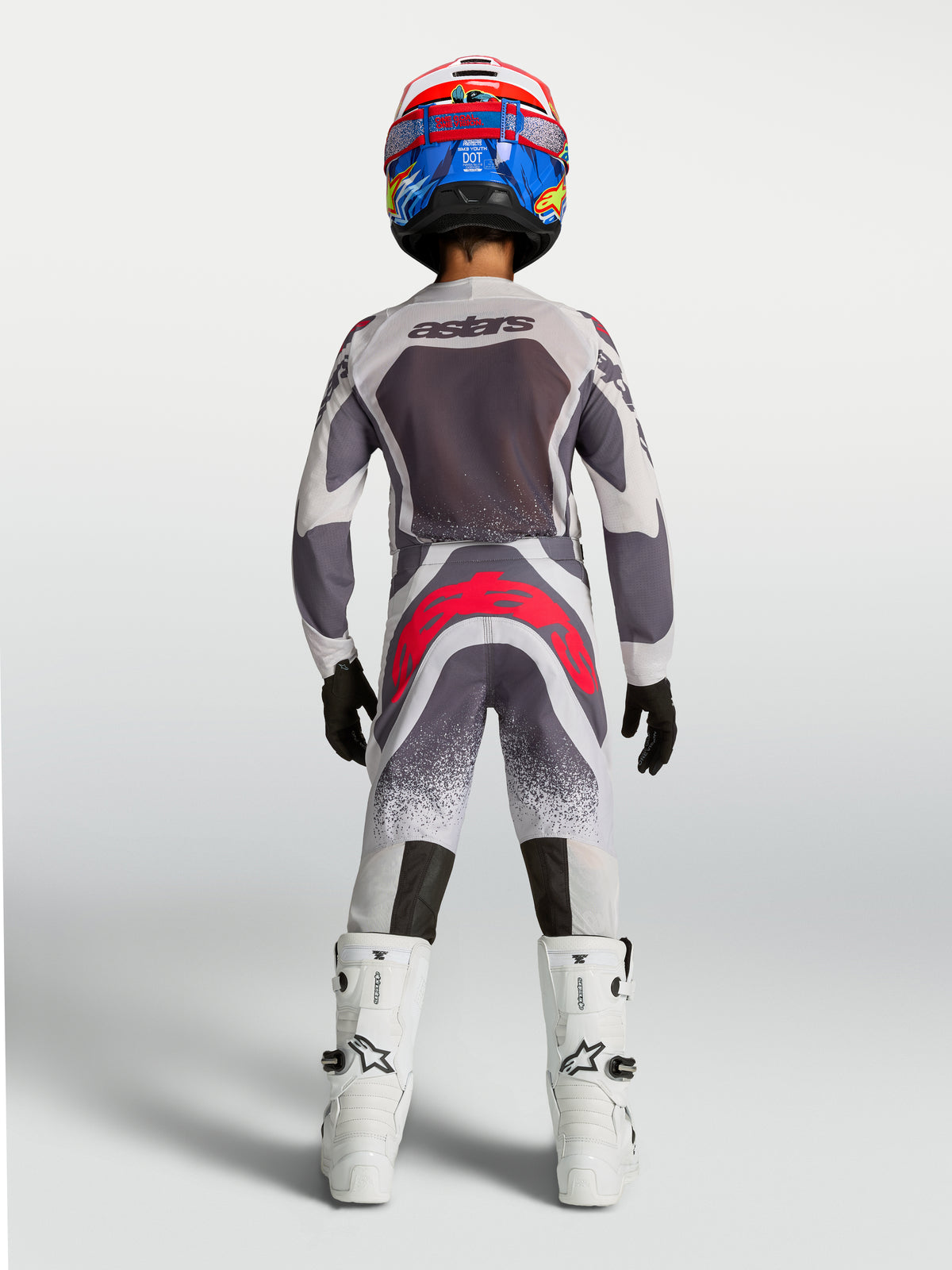Alpinestars Spodnie Supertech Swan Młodzieżowe, szare i czerwone fluo, wyścigowa odzież motocrossowa widoczna z tyłu.
