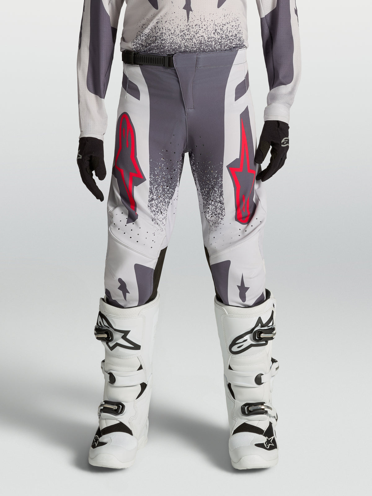 Alpinestars Supertech Swan Młodzieżowe, szare i białe spodnie motocrossowe z czerwonym logo, wyczynowy sprzęt off-road.