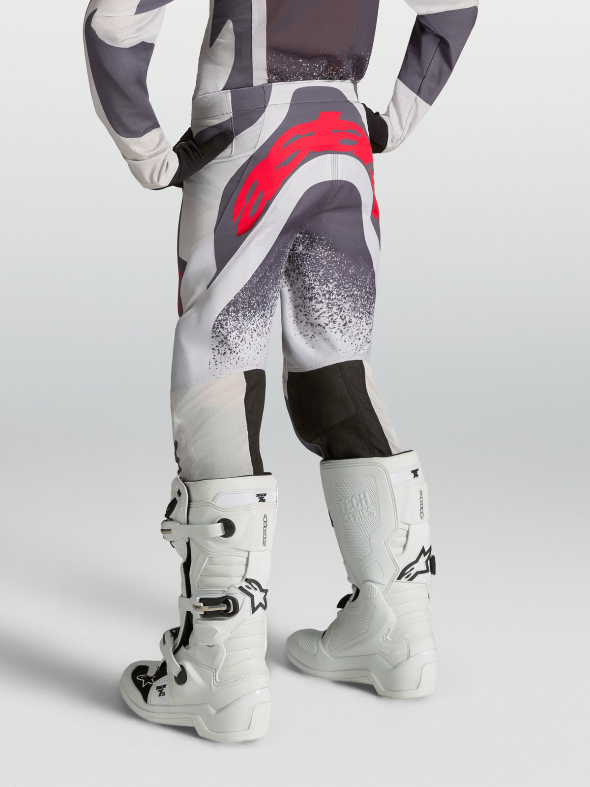 Alpinestars Spodnie Supertech Swan Młodzieżowe, szare i liliowe spodnie motocrossowe z czerwonym logo, widok z tyłu.