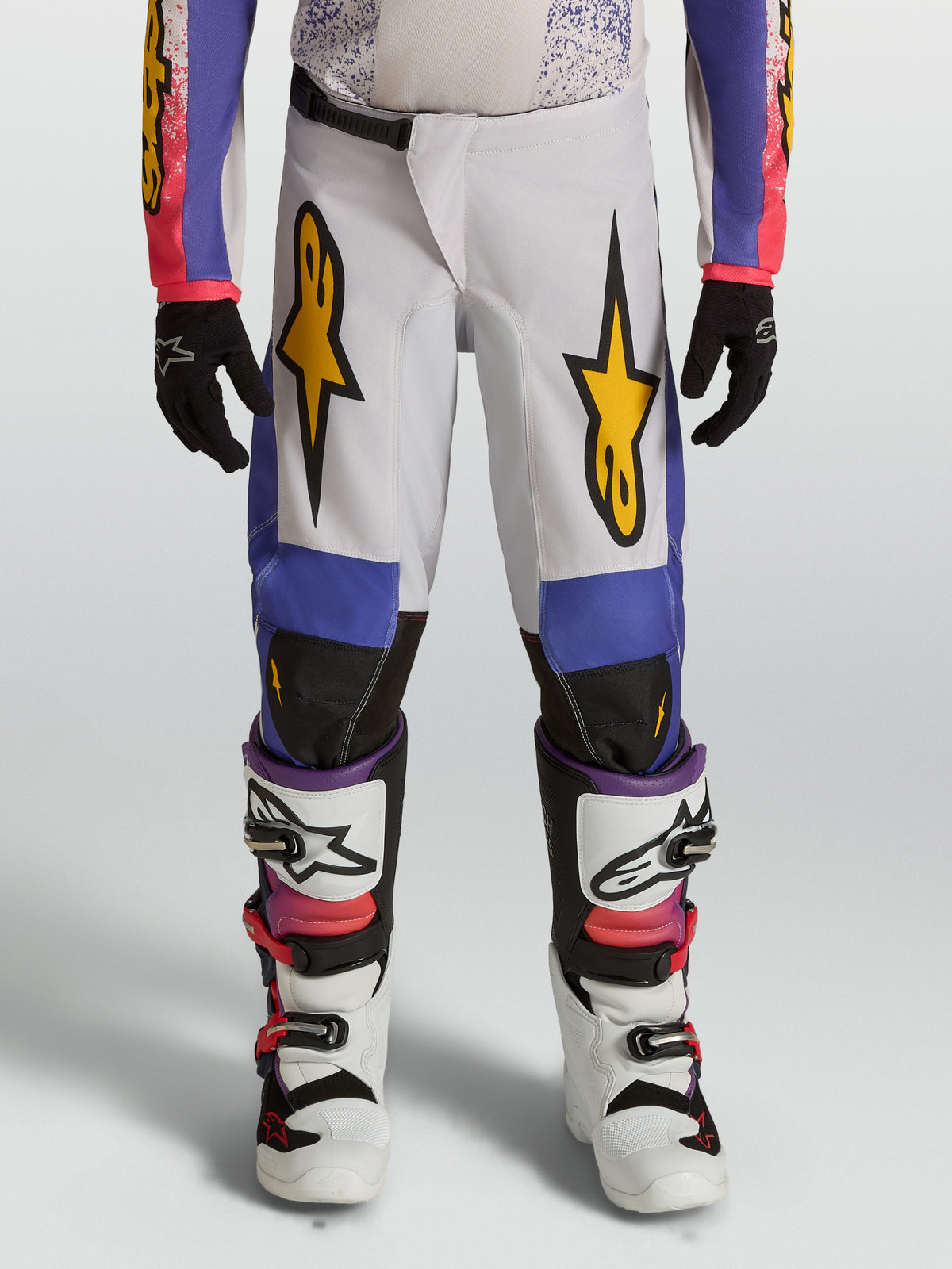 Młodzieżowe spodnie Alpinestars Fluid Drag, biało-niebieskie spodnie motocrossowe ze złotą grafiką i krojem off-road.