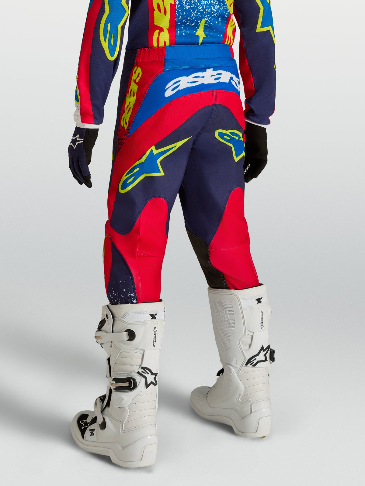 Alpinestars spodnie Fluid Drag młodzieżowe, granatowe i czerwone tekstylne spodnie motocrossowe, widok z tyłu z białymi butami