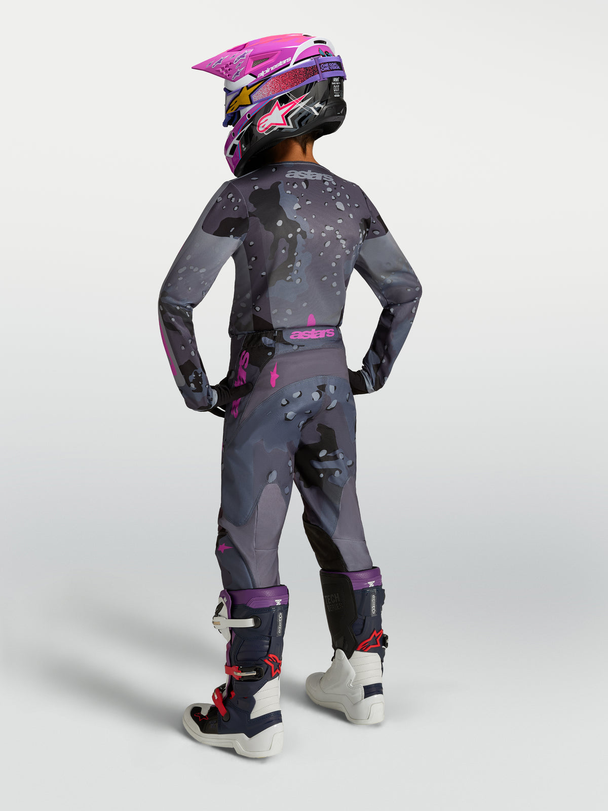 Alpinestars Młodzież Fluid Lone Gear Set 2027, szary i różowy strój motocrossowy, widok z tyłu na ridera w kasku i butach.