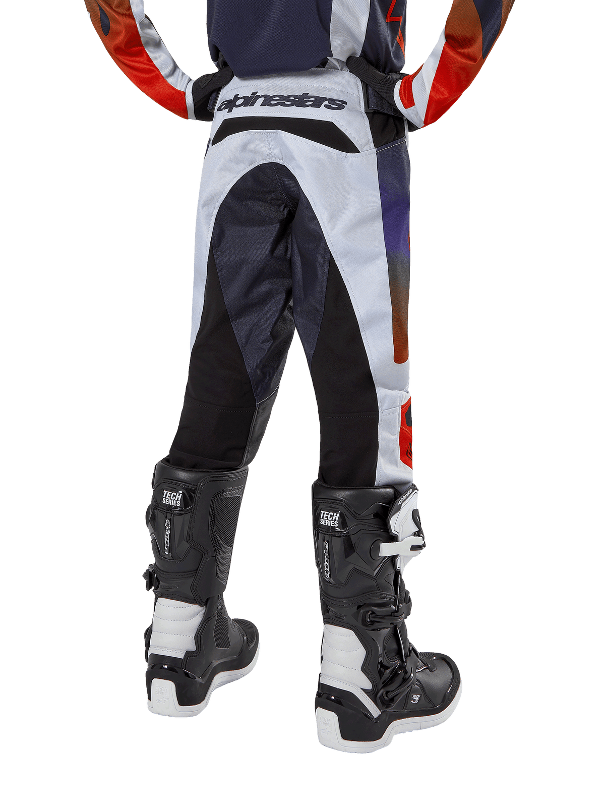 Alpinestars Youth 2024 Racer Hoen Pants, Motocross Pants, Light Gray with Hot Orange and Black accents, rear view featuring black panels on the seat and legs, bold branding on the back waist, worn with black and white motocross boots for off-road racing