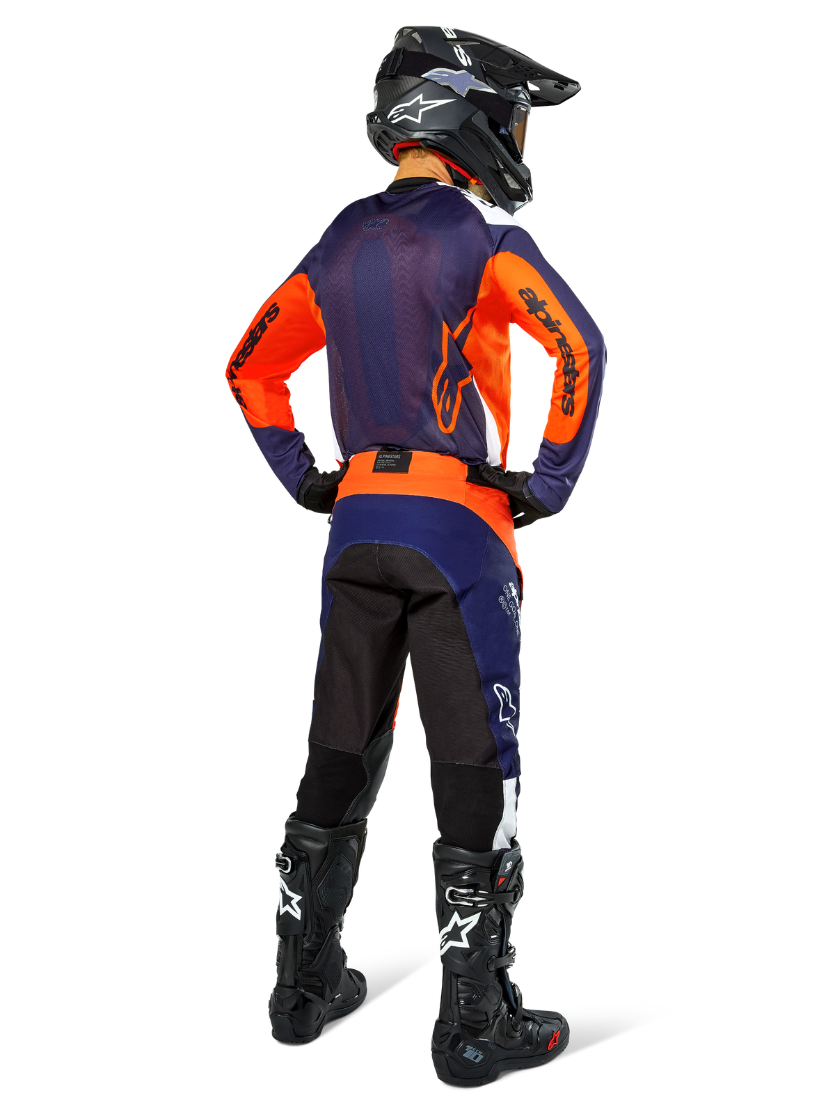 Zawodnik motocrossowy widziany od tyłu w koszulce Alpinestars Pro-Dura, granatowy, jaskrawopomarańczowy i biały, pasujące granatowo-pomarańczowe spodnie, czarny kask i czarne buty, oddychający siatkowy panel na plecach i przedłużony tył, dopasowany strój do wyścigów enduro