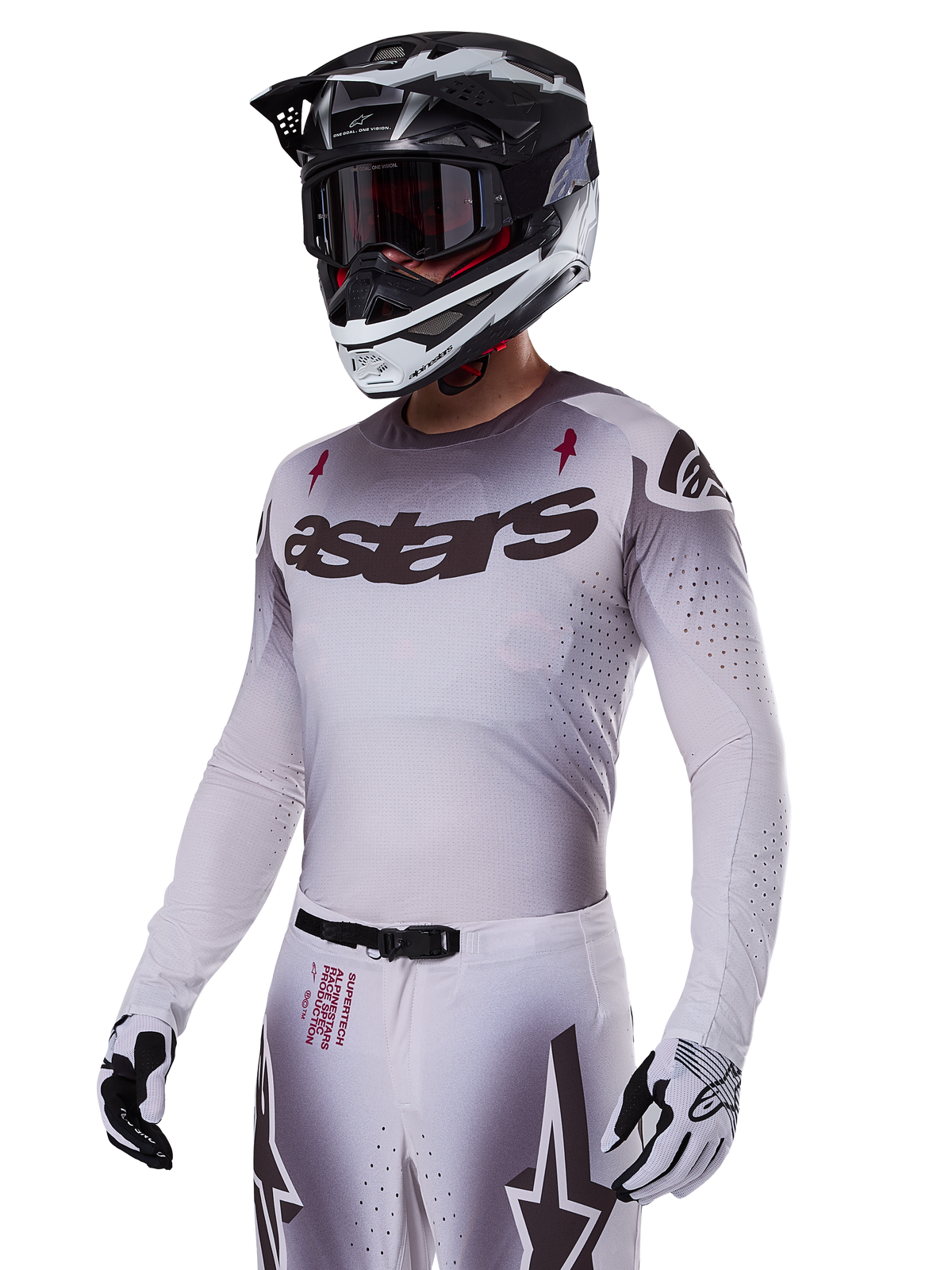 Koszulka Alpinestars Supertech Maker 2025, koszulka motocrossowa, srebrno-czarny gradient, oddychająca elastyczna siateczka z laserowo wycinanymi perforacjami, prezentowana z dopasowanymi spodniami i kaskiem, z logo „astars”, kompletny profesjonalny strój off-road