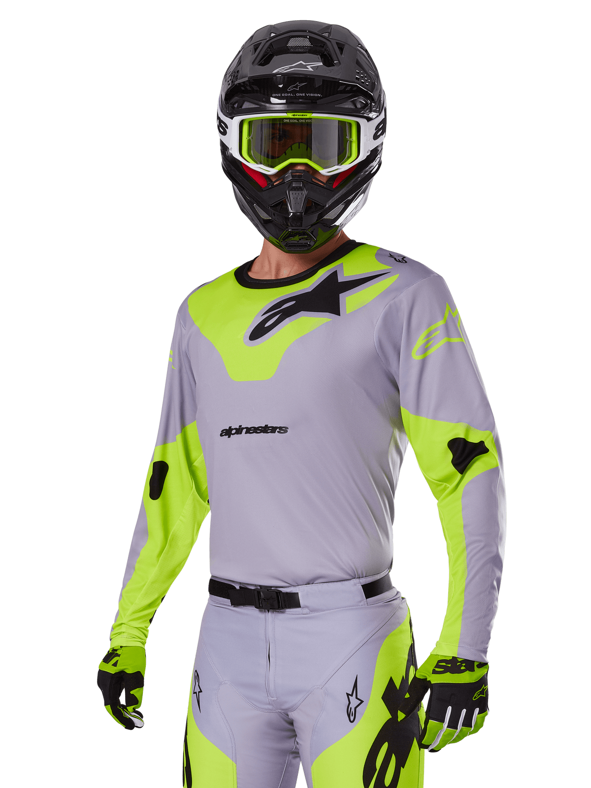 Zawodnik motocrossowy w zestawie Alpinestars 2025 Racer Veil w kolorze szarym i neonowym zielonym, jasnoszara koszulka i spodnie z wyrazistymi neonowymi żółto-zielonymi panelami i czarnym logo Alpinestars, dopasowane rękawice i czarny kask z neonowymi zielonymi goglami, profesjonalna odzież wyścigowa off-road.