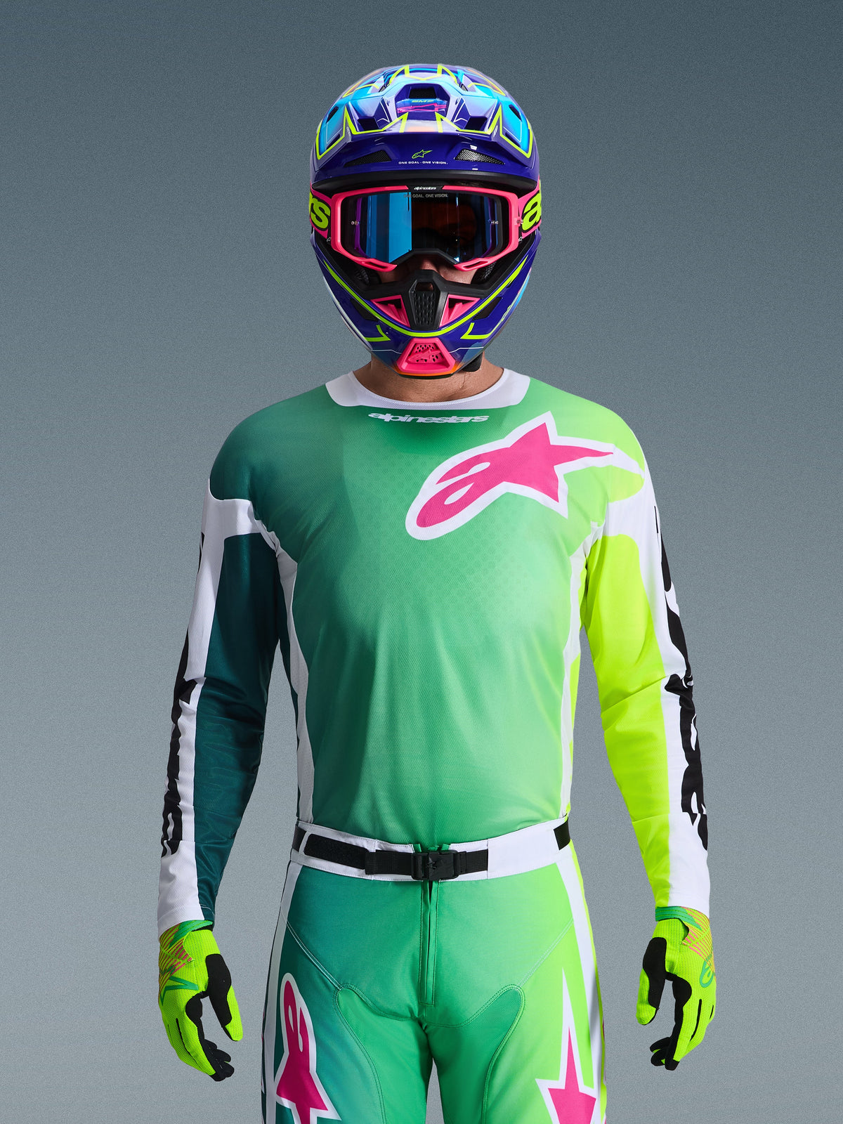 Zestaw Alpinestars 2026 Racer Portl, zawodnik motocrossowy w koszulce z zielono-żółtym gradientem i różowym logo Astars, pasujące spodnie, kolorowy niebiesko-różowy kask z niebieskimi goglami i limonkowe rękawice, profesjonalny strój wyścigowy off-road