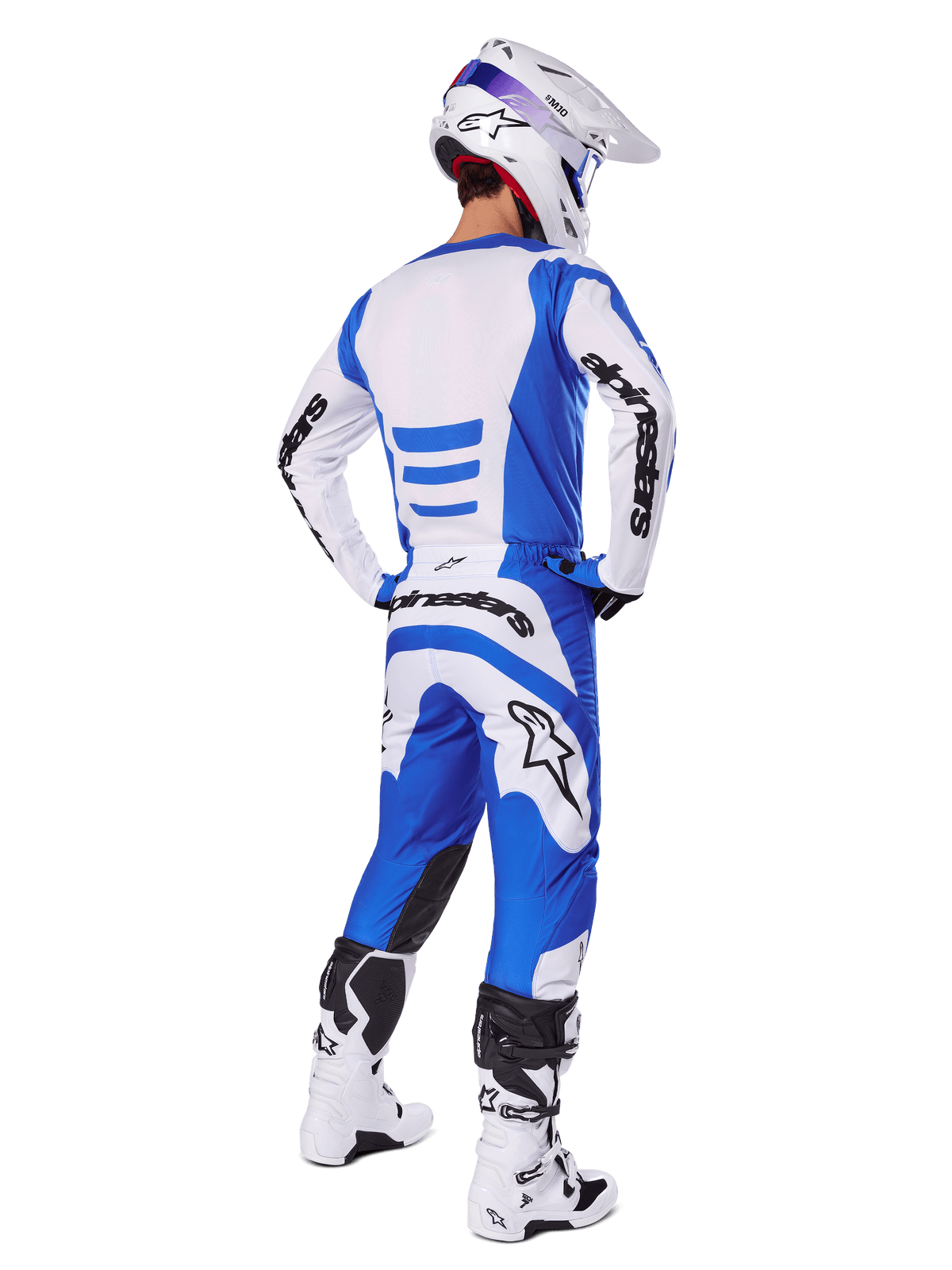 Jeździec motocrossowy widziany od tyłu w zestawie Alpinestars 2025 Fluid Haul, niebiesko-biała koszulka i pasujące spodnie, biały kask z niebieskimi akcentami oraz biało-czarne buty wyścigowe, dopasowany strój do jazdy terenowej