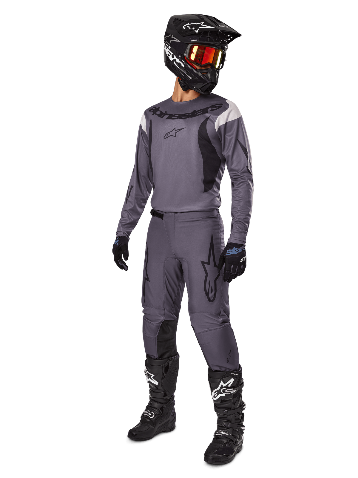 Motocross rider wearing Alpinestars 2025 Fluid Haul Gear Set in Gray, including gray jersey and pants with black accents, black helmet with reddish goggles, black gloves, and black boots with white logos, complete off-road racing outfit