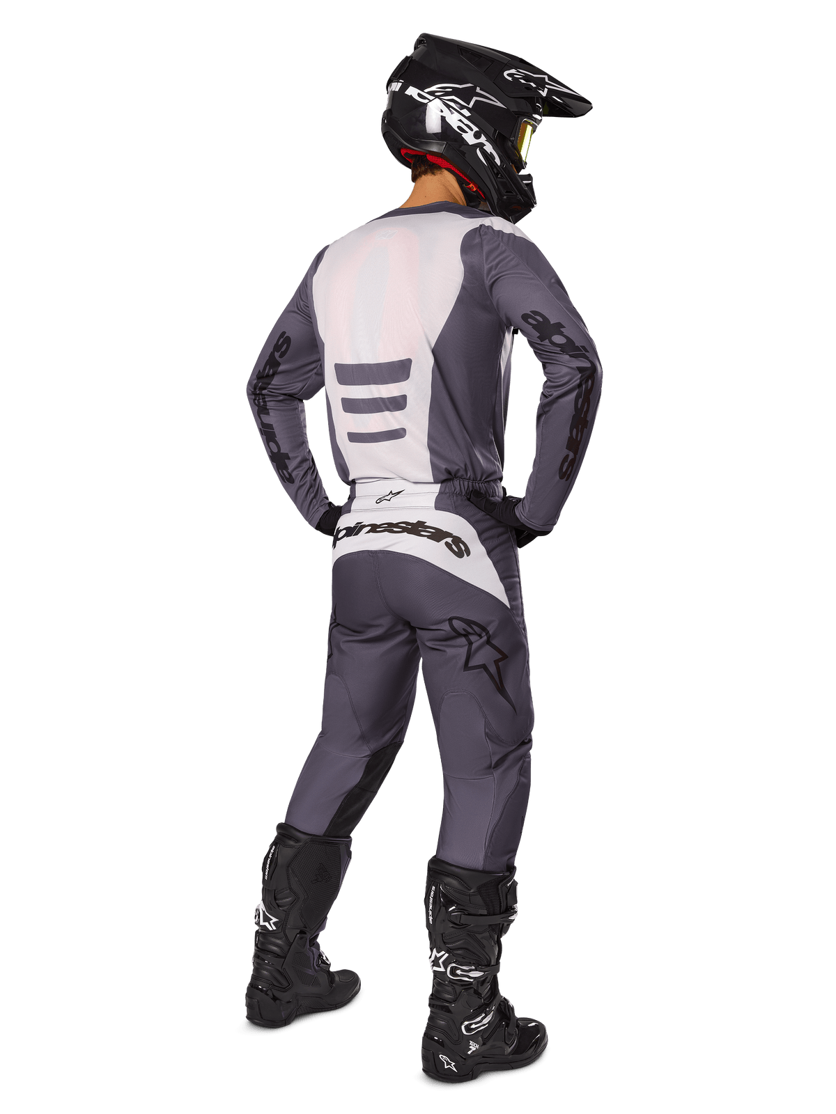 Motocross rider from the back wearing Alpinestars 2025 Fluid Haul Gear Set, Gray and White jersey and matching pants, black helmet with yellow goggles, black motocross boots, complete racing gear for off-road performance