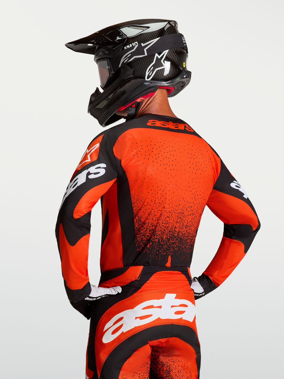 Koszulka Techstar Swan, męska koszulka motocrossowa w kolorze czerwono-czarnym, laserowo cięta wentylacja i sportowy krój wyścigowy, widok od tyłu na zawodnika w kasku.