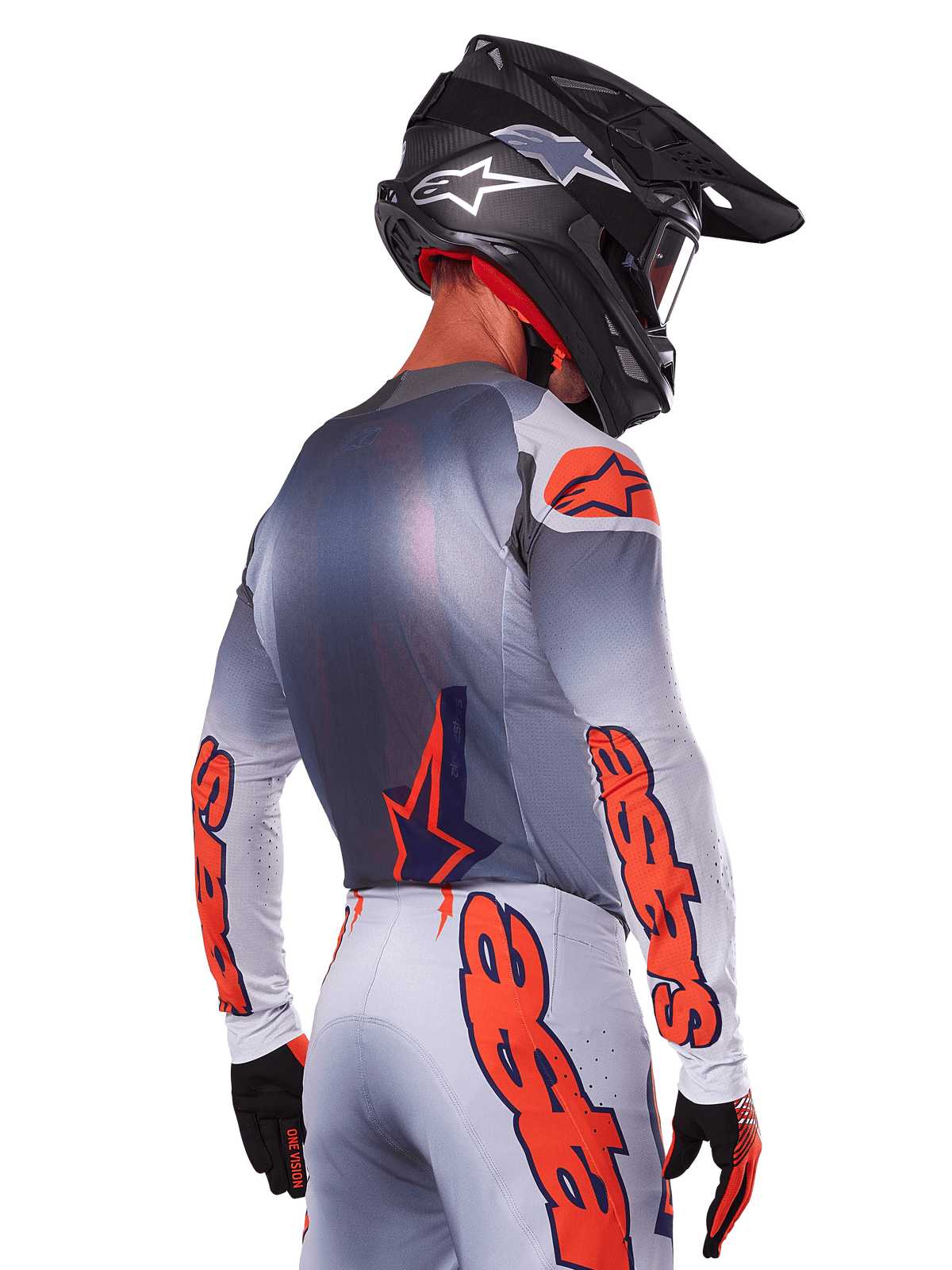 Motocyklista motocrossowy widoczny od tyłu w koszulce Alpinestars 2025 Supertech Lipan w kolorze Gray Orange Fluo, z wyraźnymi pomarańczowymi logotypami na rękawach i plecach, w zestawie z dopasowanymi spodniami i czarnym kaskiem, profesjonalny strój wyścigowy do jazdy w terenie.