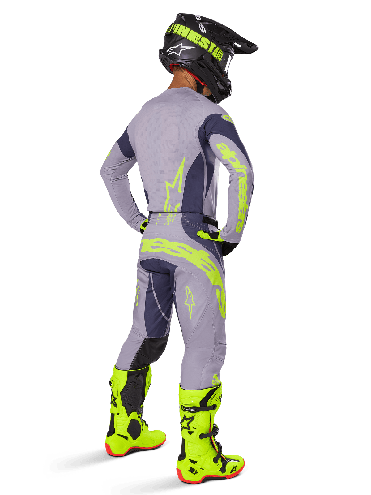 Motocross rider from a rear view wearing the Alpinestars 2025 Techstar Dreem Gear Set, Gray and Dark Gray with fluorescent yellow branding, matching jersey and pants, black helmet with yellow accents, and bright fluorescent yellow boots, coordinated professional motocross racing outfit.