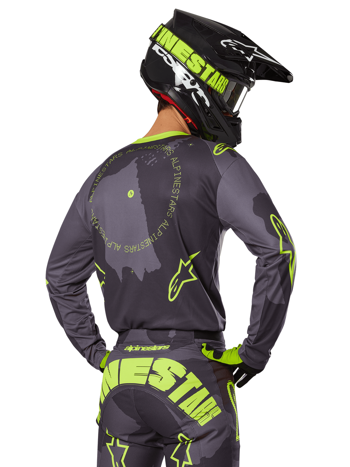 Motocyklista motocrossowy widziany od tyłu w zestawie Racer Hollow 2025, szara koszulka z neonowożółtym napisem w kształcie koła i logo z gwiazdą, pasujące szaro-żółte spodnie z wyraźnym brandingiem na siedzeniu, czarno-limonkowy kask, dopasowany strój do wyścigów terenowych