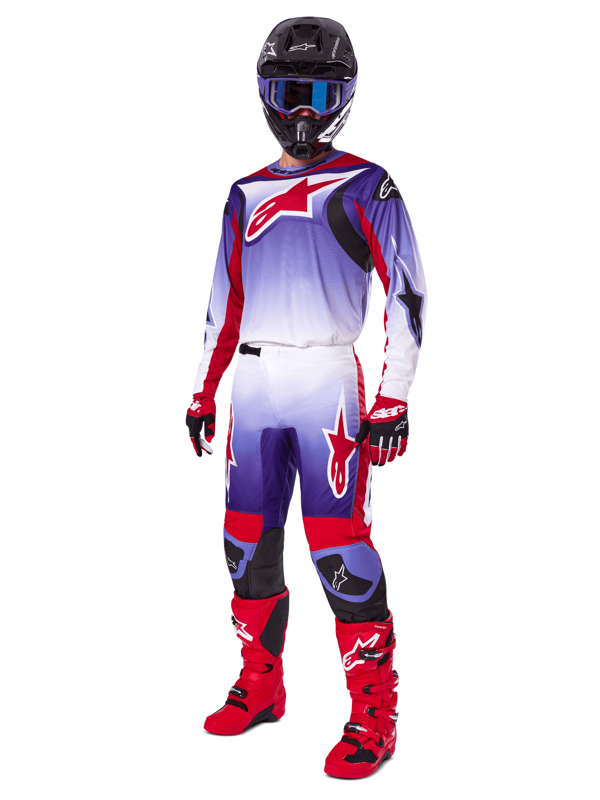 Motocyklista motocrossowy w zestawie Alpinestars 2025 Fluid Wurx, fioletowo-jaskrawoczerwona koszulka z białymi akcentami, pasujące spodnie motocrossowe, jaskrawoczerwone buty, czarny kask z niebieskimi goglami i czerwono-czarne rękawice, pełny profesjonalny zestaw wyścigowy off-road