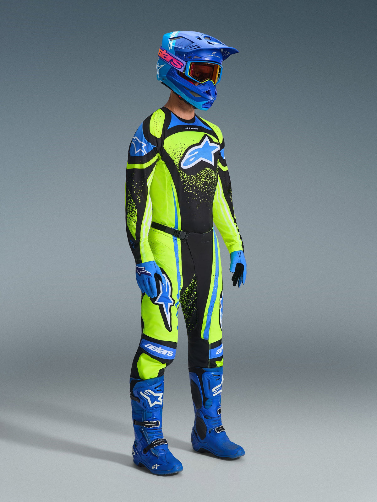 Zawodnik motocrossowy w pełnym stroju wyścigowym, koszulka Techstar Nomur 2026 w kolorze ciemnogranatowym i fluorescencyjnym żółtym, pasujące spodnie, niebieski kask z goglami, niebieskie buty i rękawice, dopasowany zestaw do wyścigów terenowych