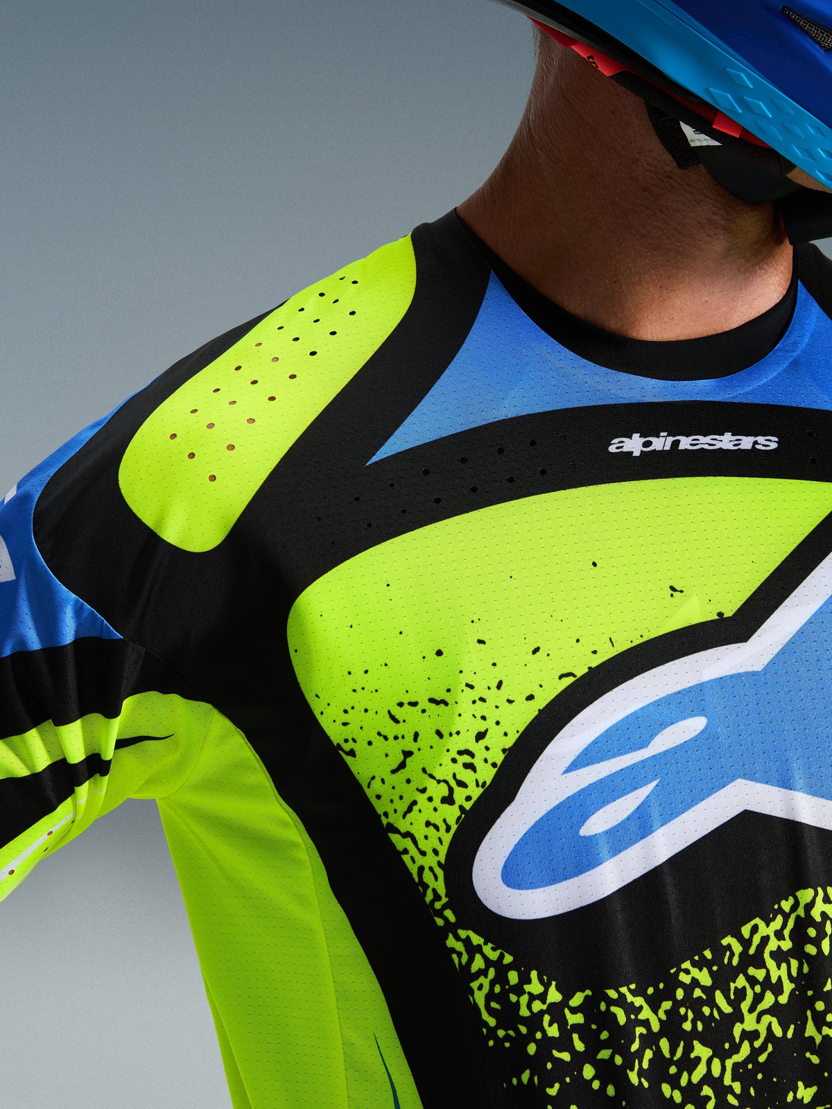 Alpinestars 2026 Techstar Nomur Jersey, koszulka motocrossowa, żółty fluo, ciemny granatowy i błękit UCLA, zbliżenie na klatkę piersiową i ramię pokazujące laserowo wycinane perforacje dla wentylacji oraz logo Alpinestars, wyczynowa odzież do wyścigów terenowych