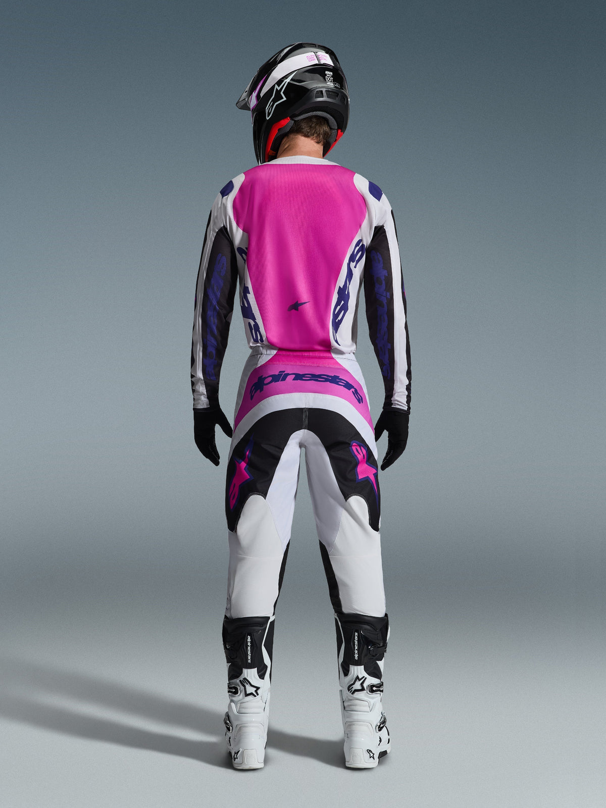 Alpinestars 2026 Fluid Grid Jersey and matching pants, Motocross Gear Set, Pink White and Purple, rear view showing ergonomic athletic fit, worn with a black helmet and white boots, designed for off-road performance.