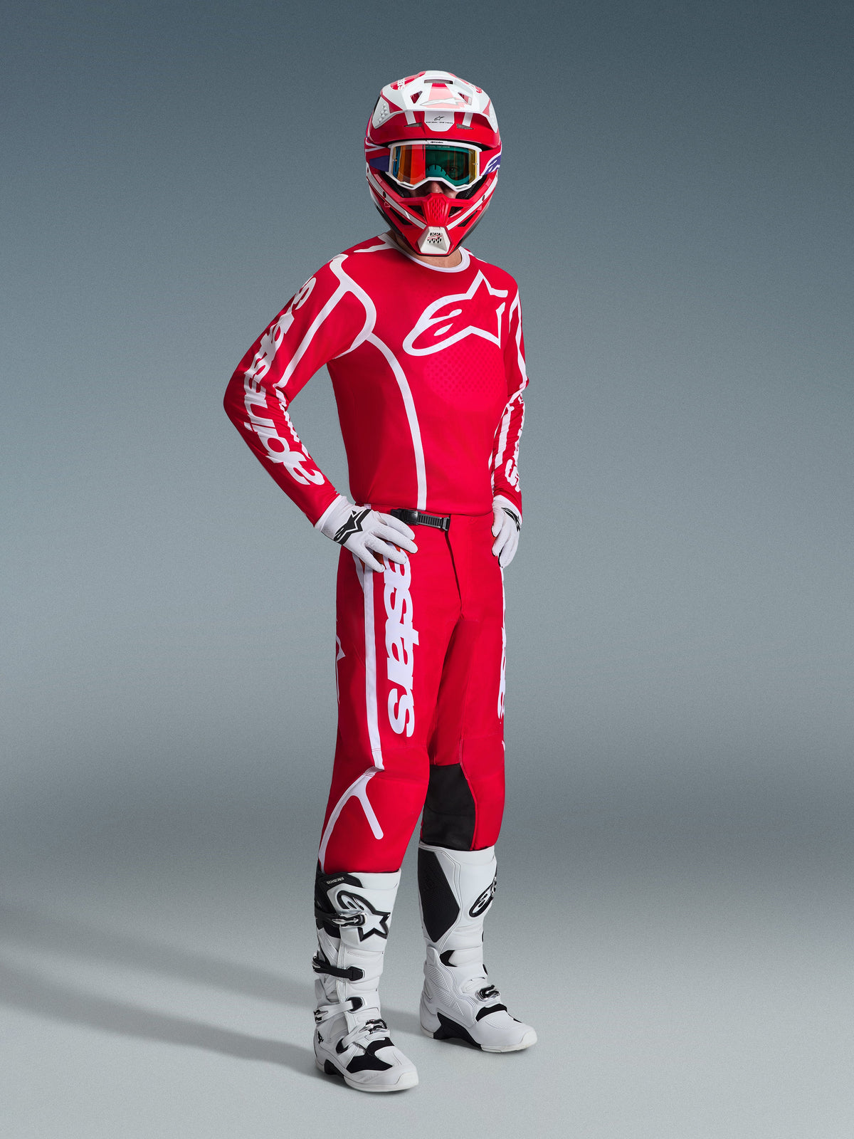 Motocyklista w zestawie Alpinestars 2026 Fluid Apex, czerwona koszulka z dużym białym logo, czerwone spodnie z białymi akcentami, biało-czerwony kask, białe buty i rękawice motocrossowe, skoordynowany strój do wyścigów off-road