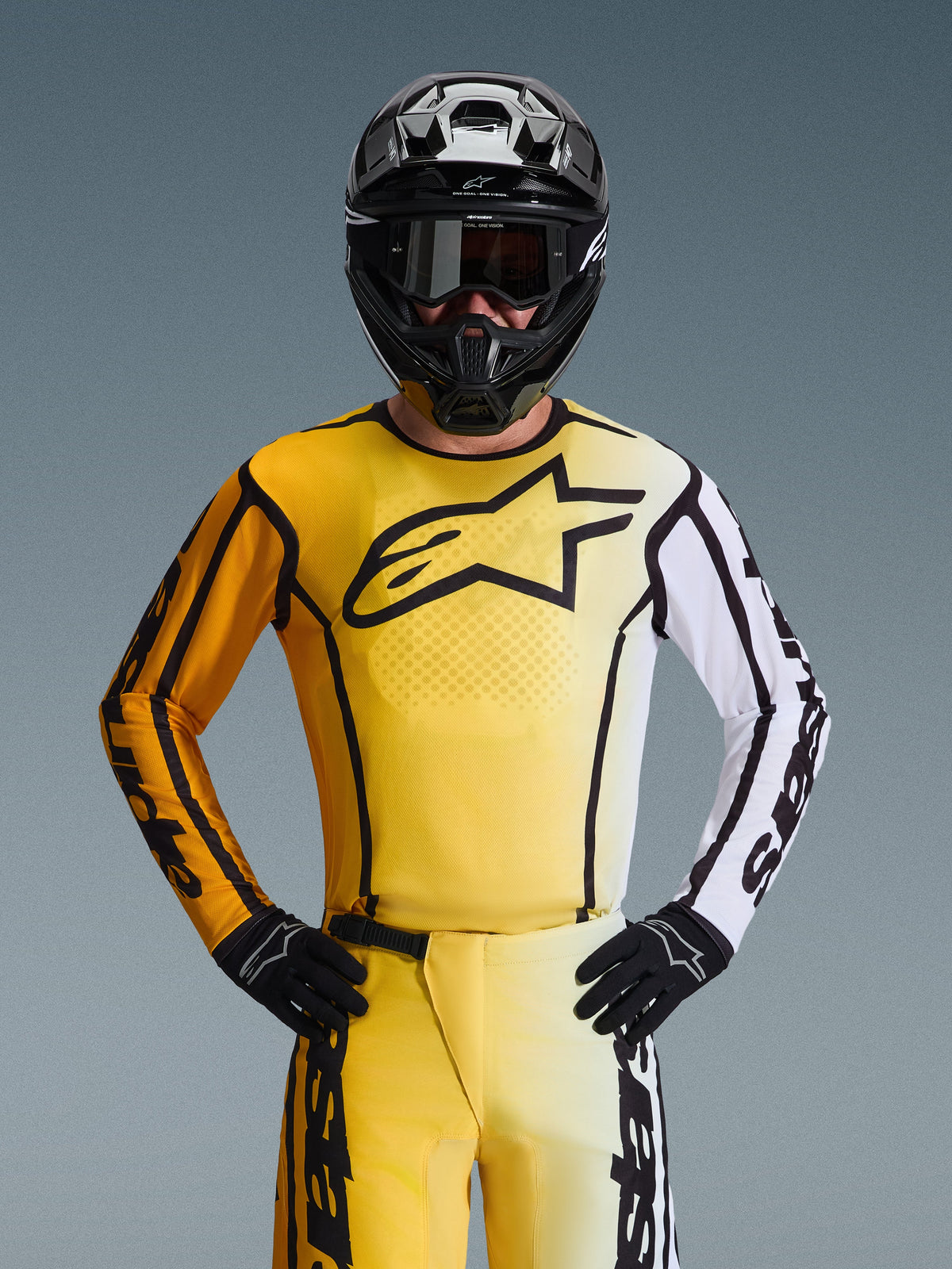 Motocross rider wearing the Alpinestars 2026 Fluid Apex Gear Set, yellow and white jersey with large black star logo, matching yellow and white pants, black helmet with black goggles, and black gloves, coordinated outfit for off-road racing